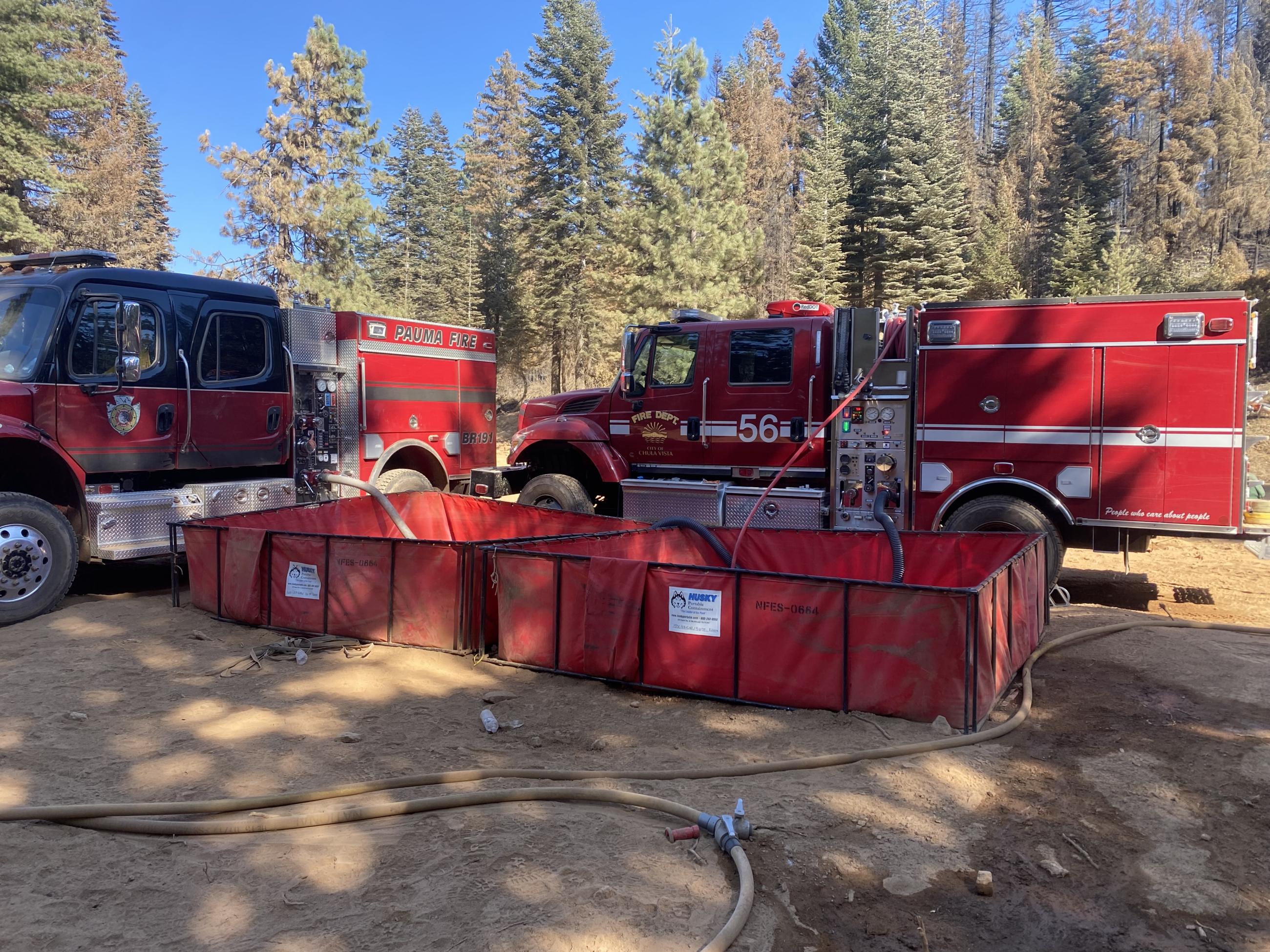 2 fire engines with hoses in 2 portable water tanks receive or deliver water