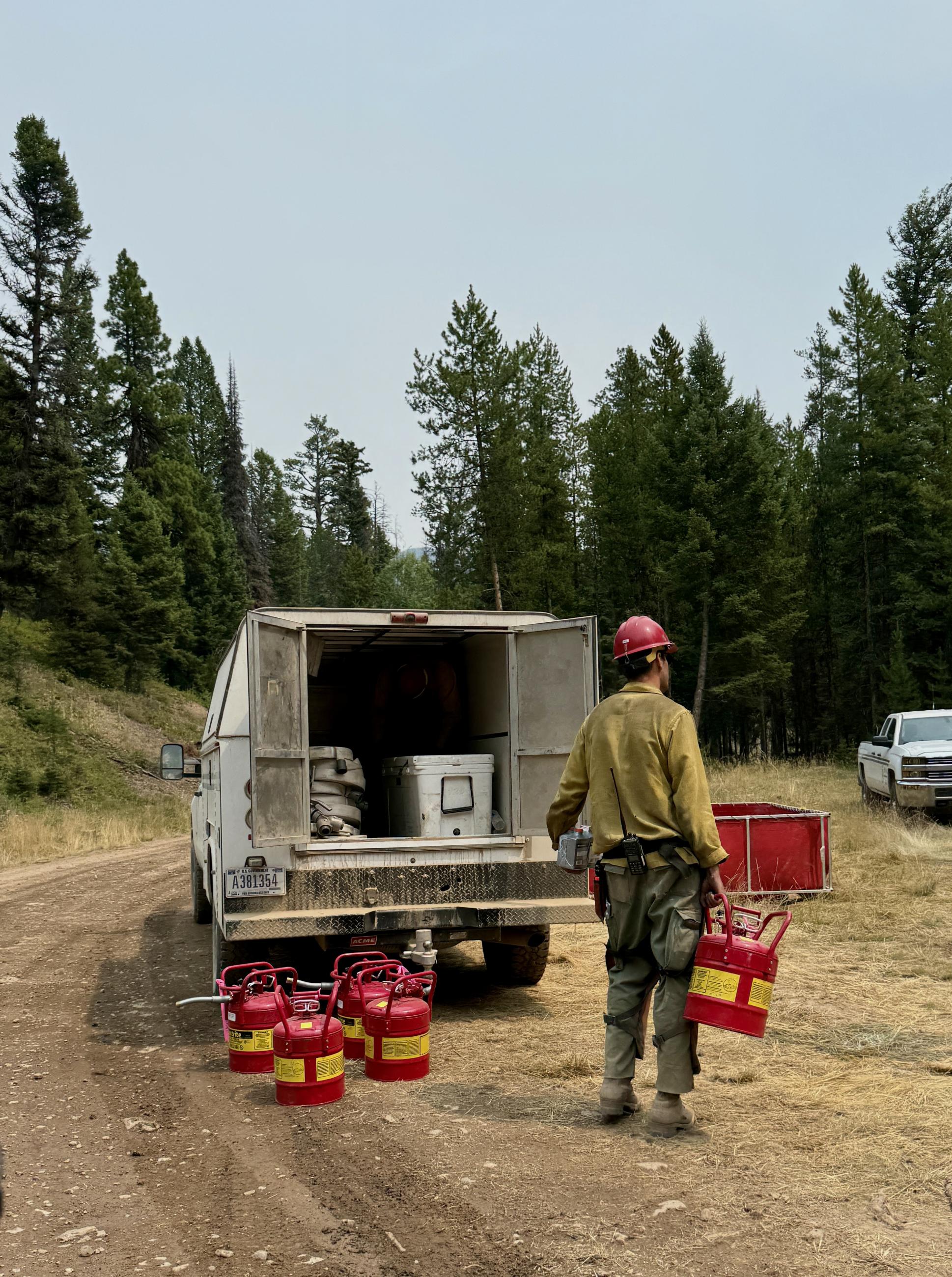 Firefighters load fuel tanks and hose to take back to the fireline.