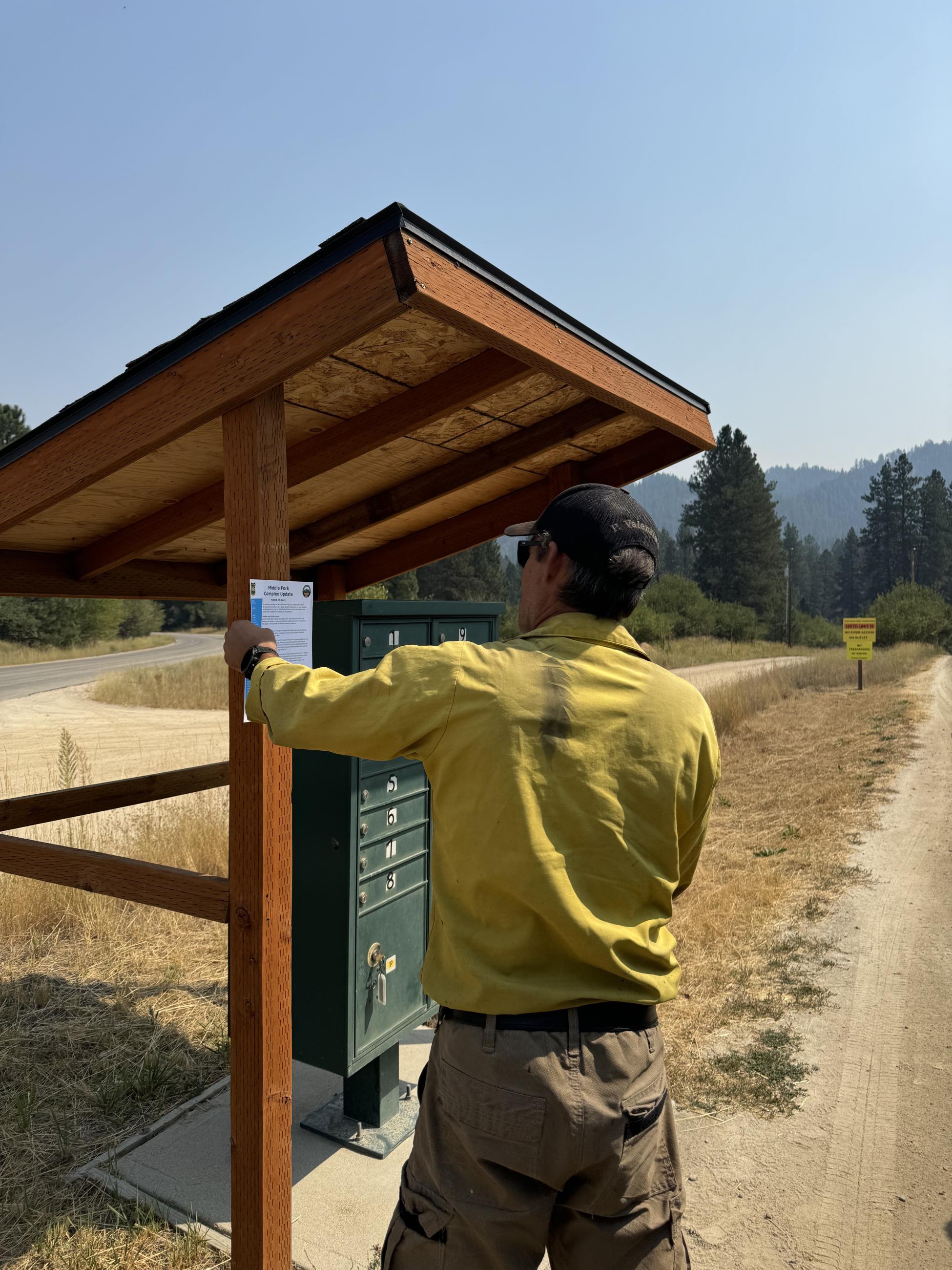 A firefighter posts an informational flyer next to a group of mailboxes