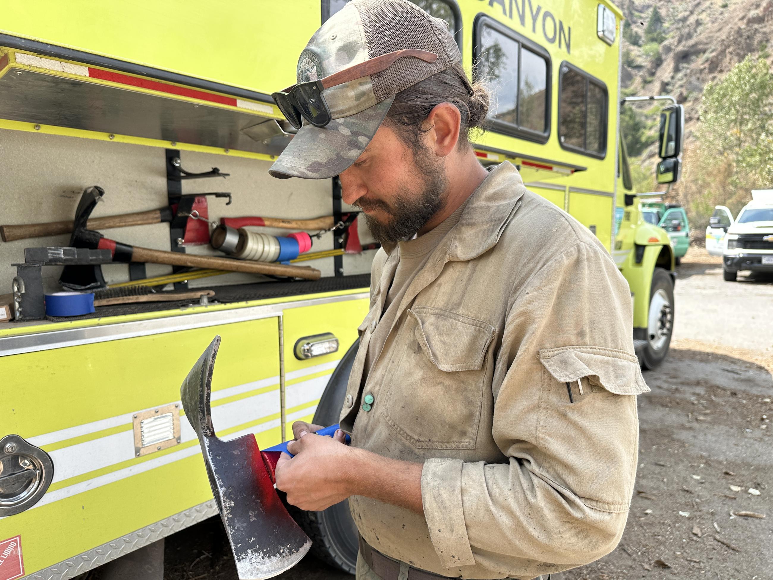 A firefighter puts tape on a firefighting tool handle.