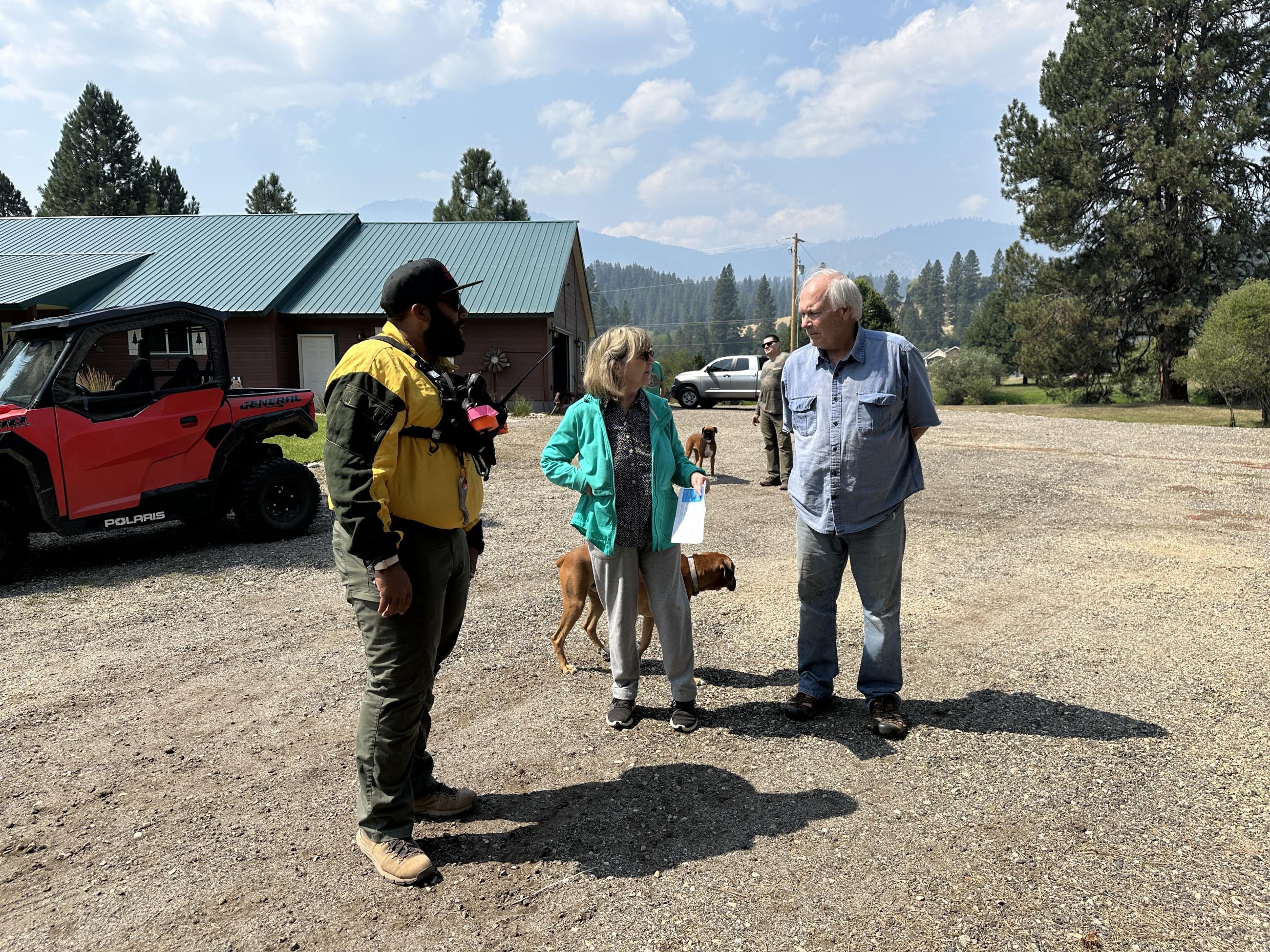 A firefighter with the Structure Protection Group visits with homeowners on their property.