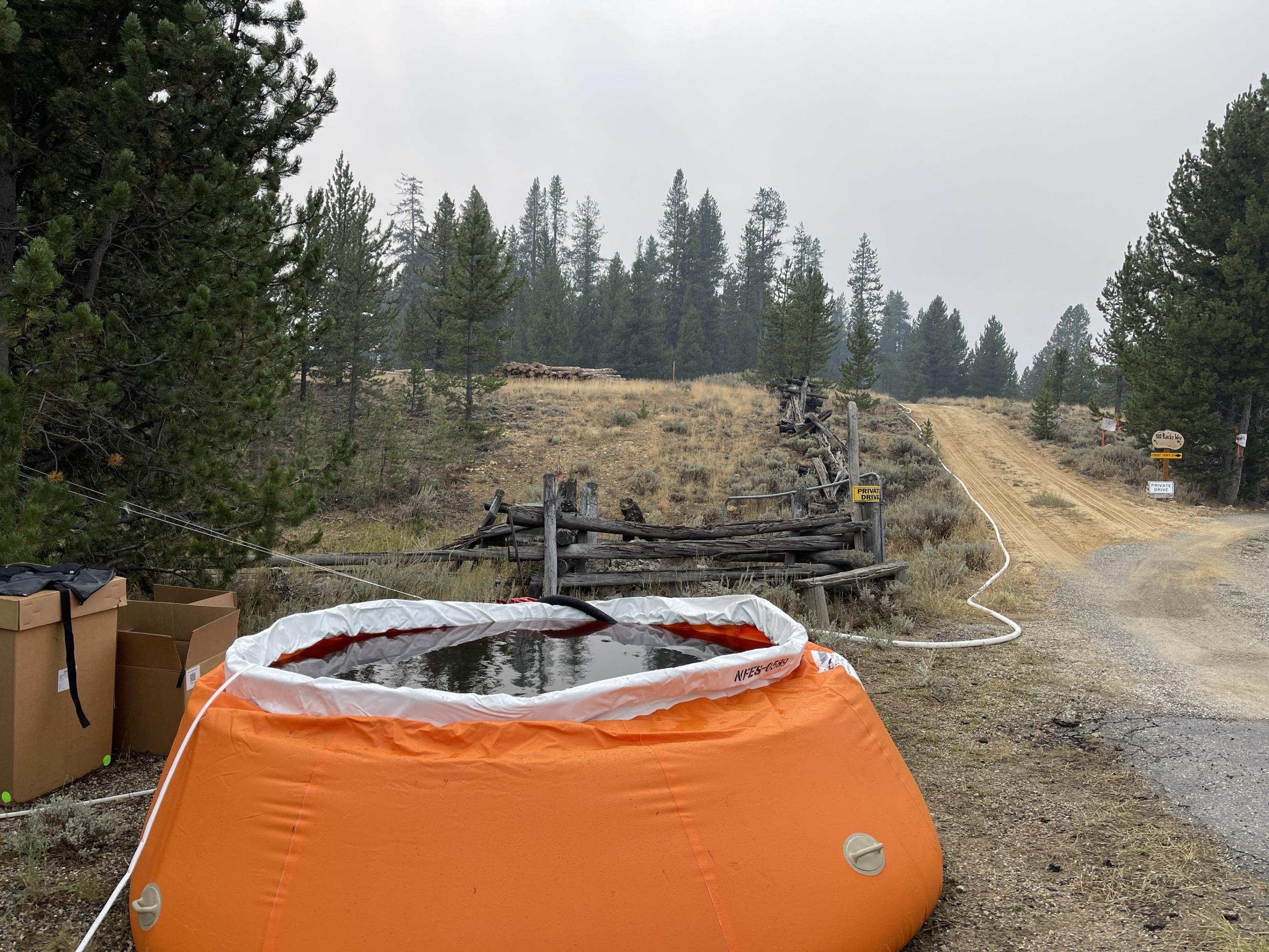 a large orange portable water tank is used as a water source for structure protection