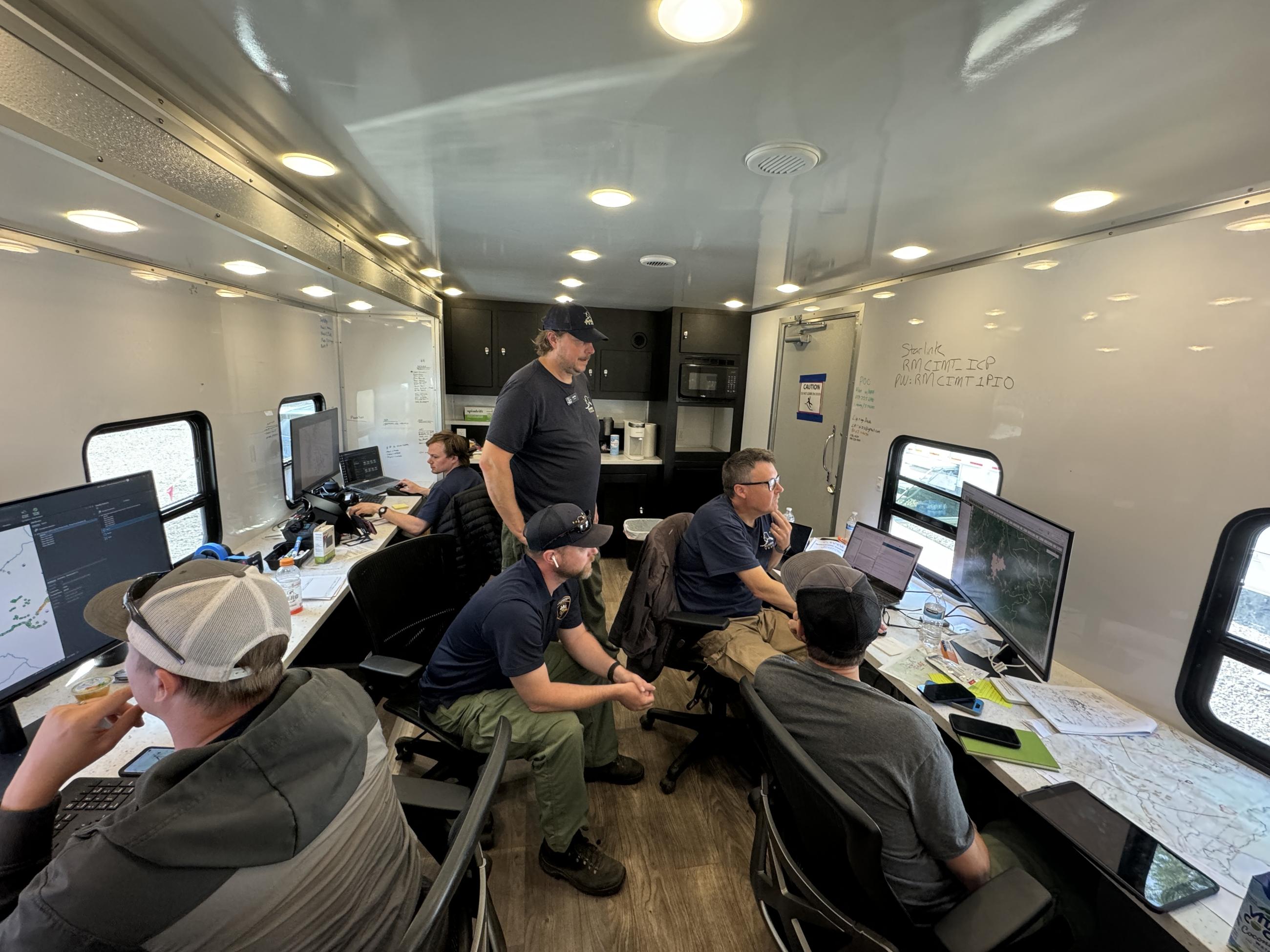 People in trailer stand around computers