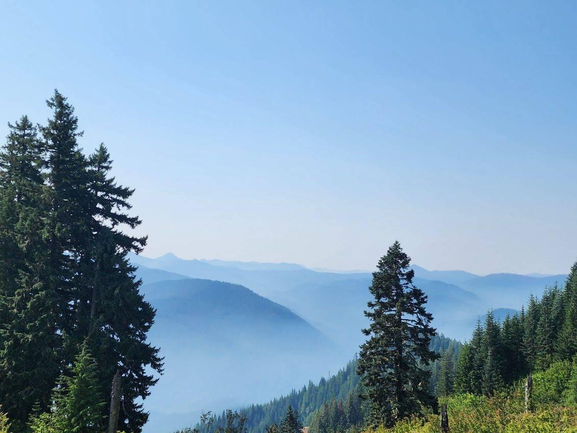 Smoke settles into valleys at an overlook on a sunny day