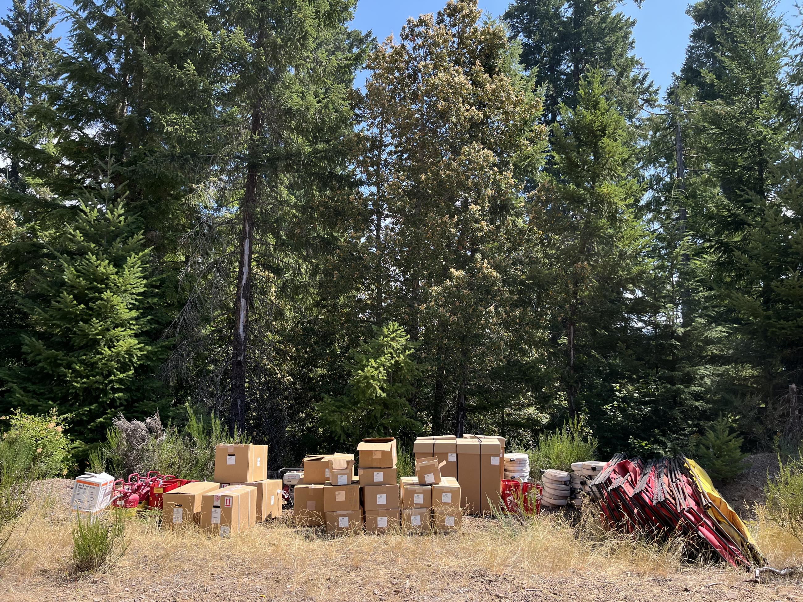 A row of boxes, hoses and other various tools sit in front of a forest