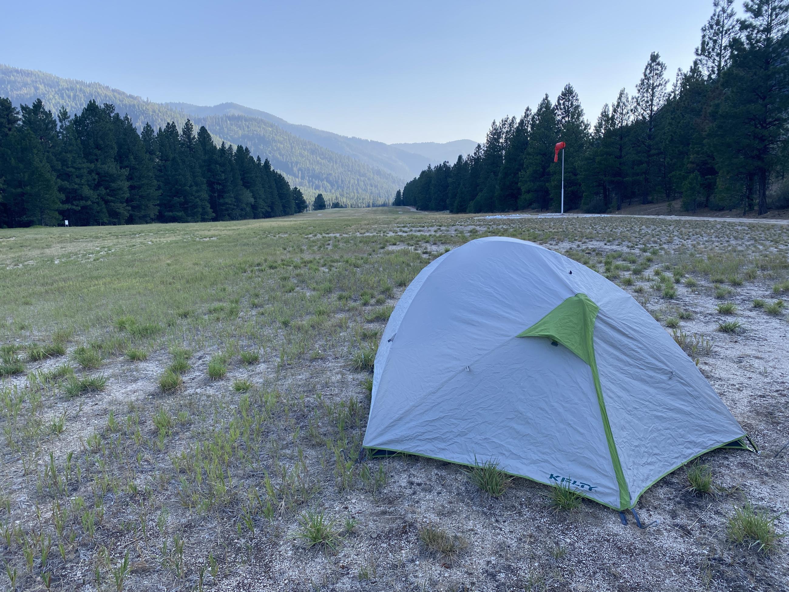 picture of tent on grassy airstrip in the forest