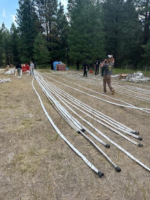 Picture displays firefighters rolling up hose that was used on the Bulltrout Fire.