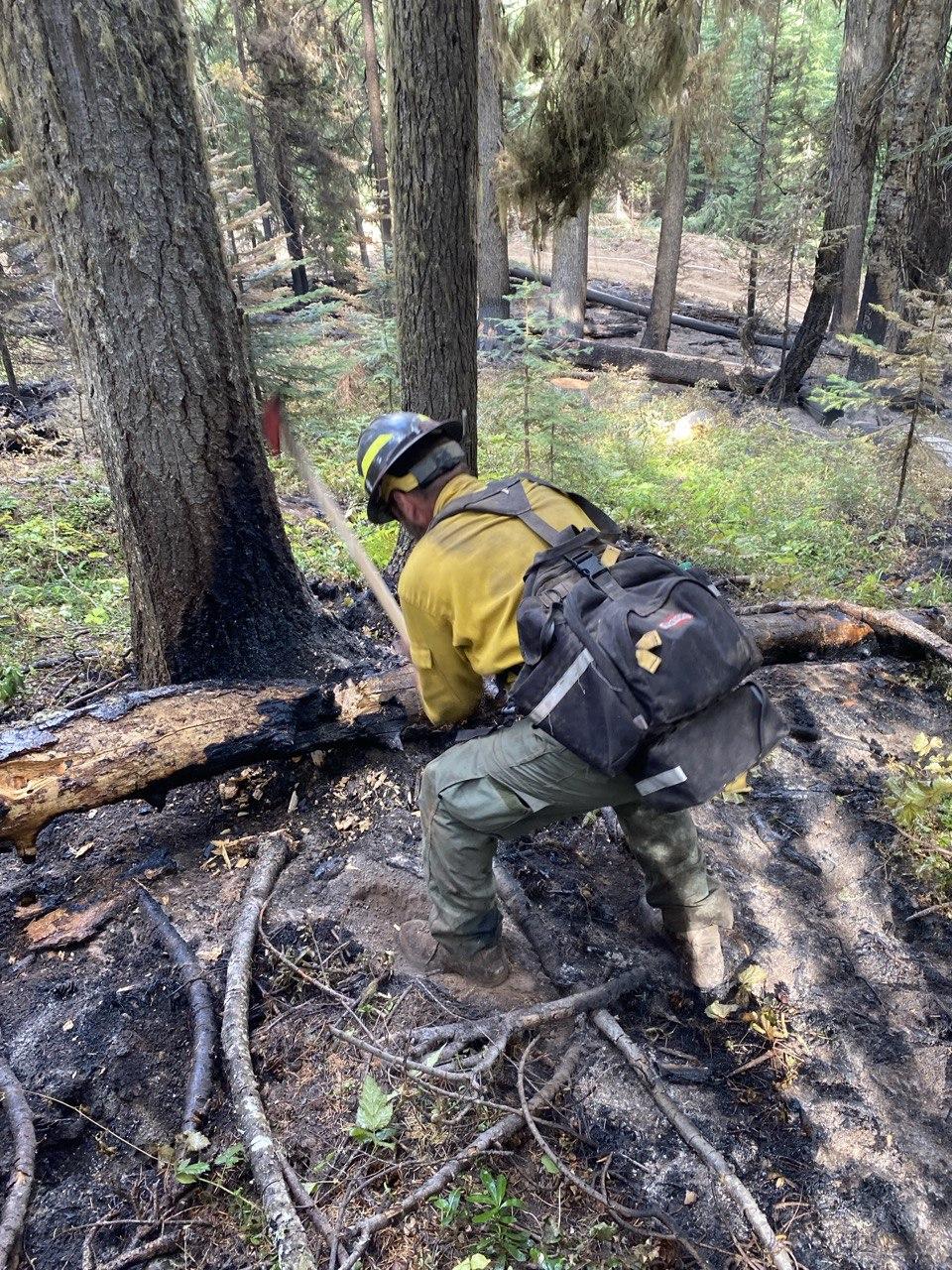 Firefighter using an axe on a burned log