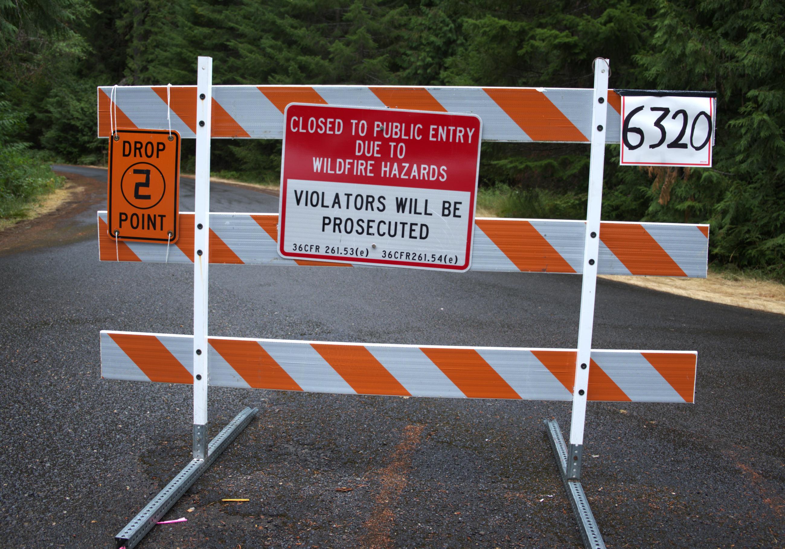 Orange and white barricade stating ROAD CLOSED