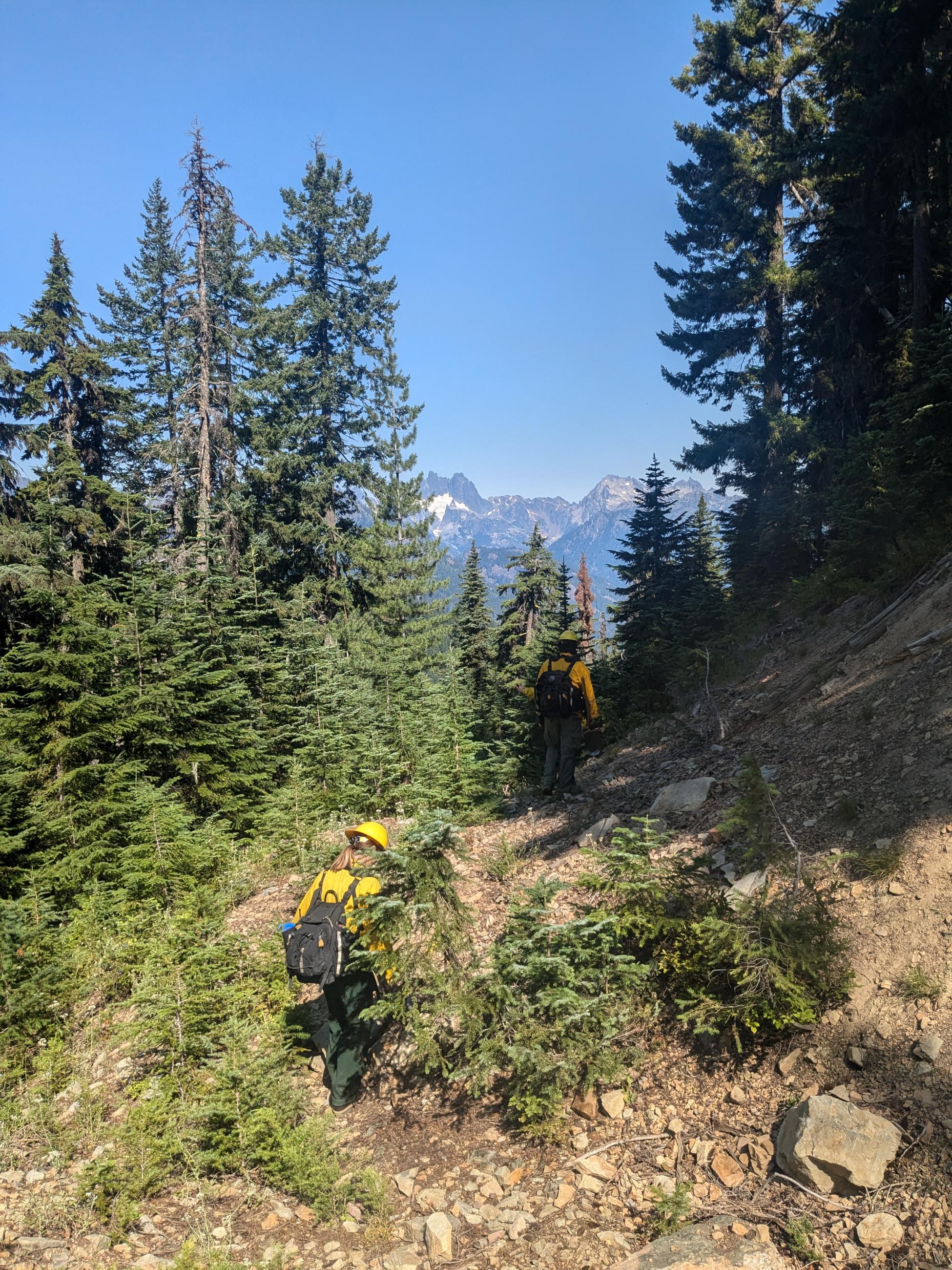 Two firefighters hike in steep terrain
