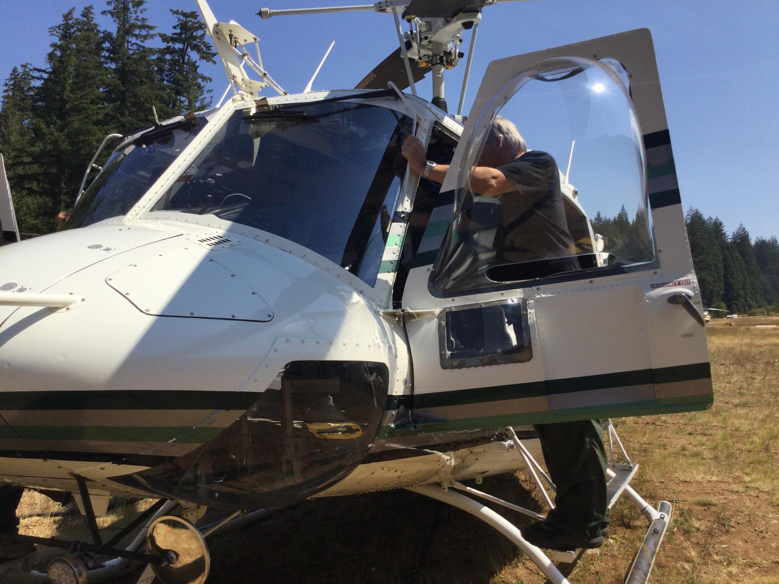 Pilot stands on helicopter with door open