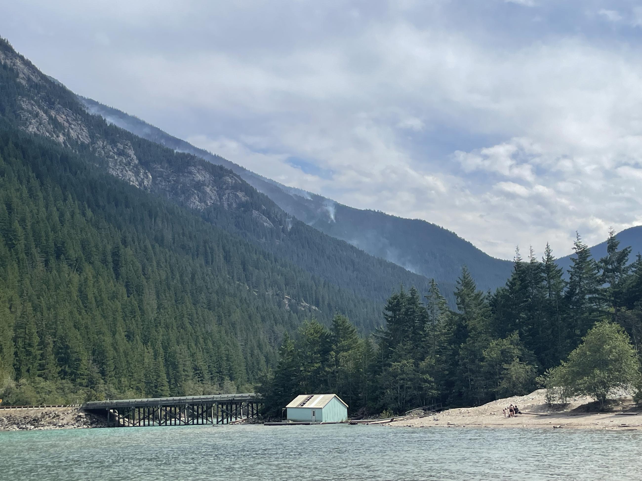 Smoke wafts through a steep forested mountain slope 