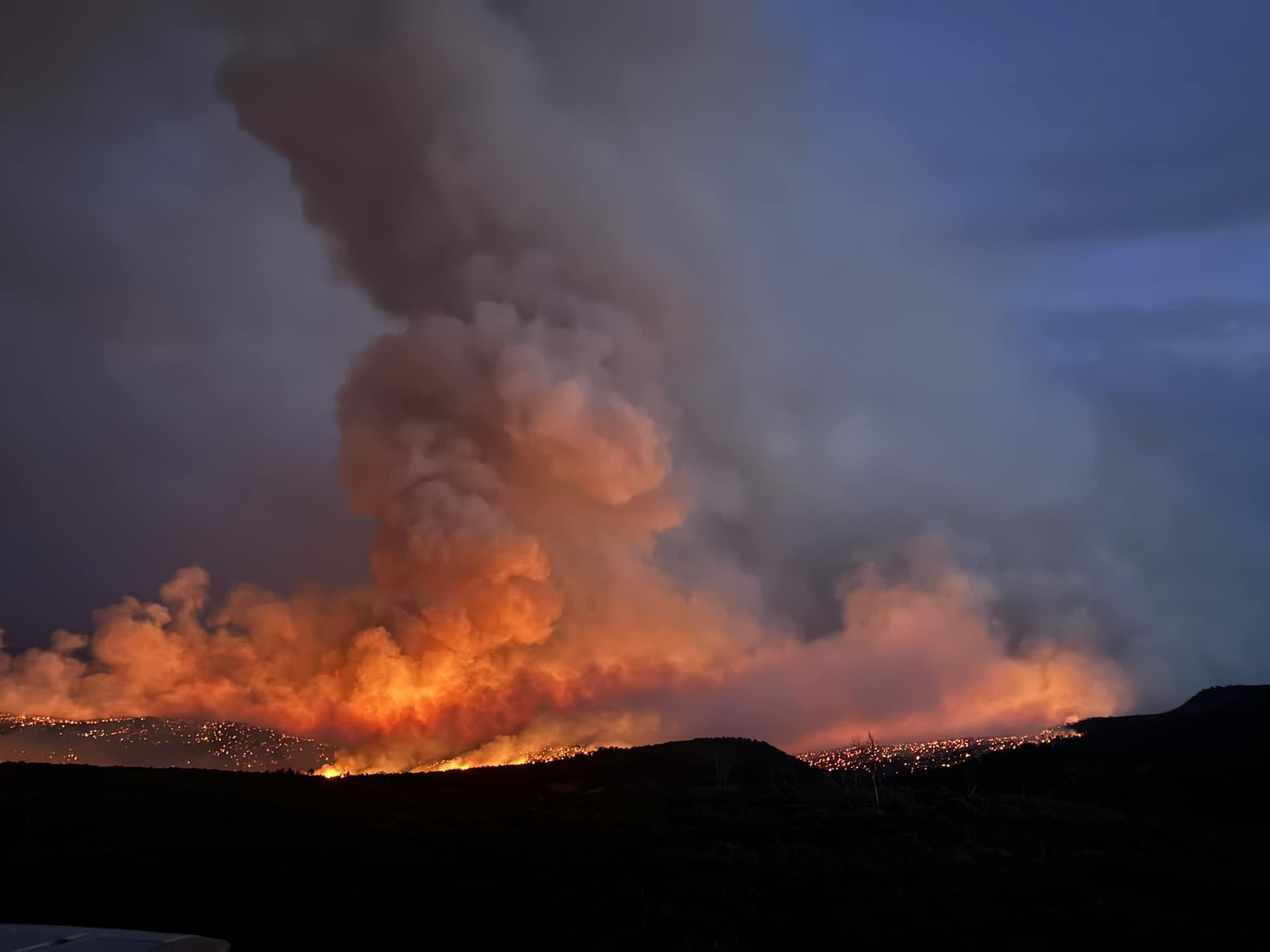 The photo is a night shot of the bucktail fire. The large orange glow emits black smoke into a dark sky.