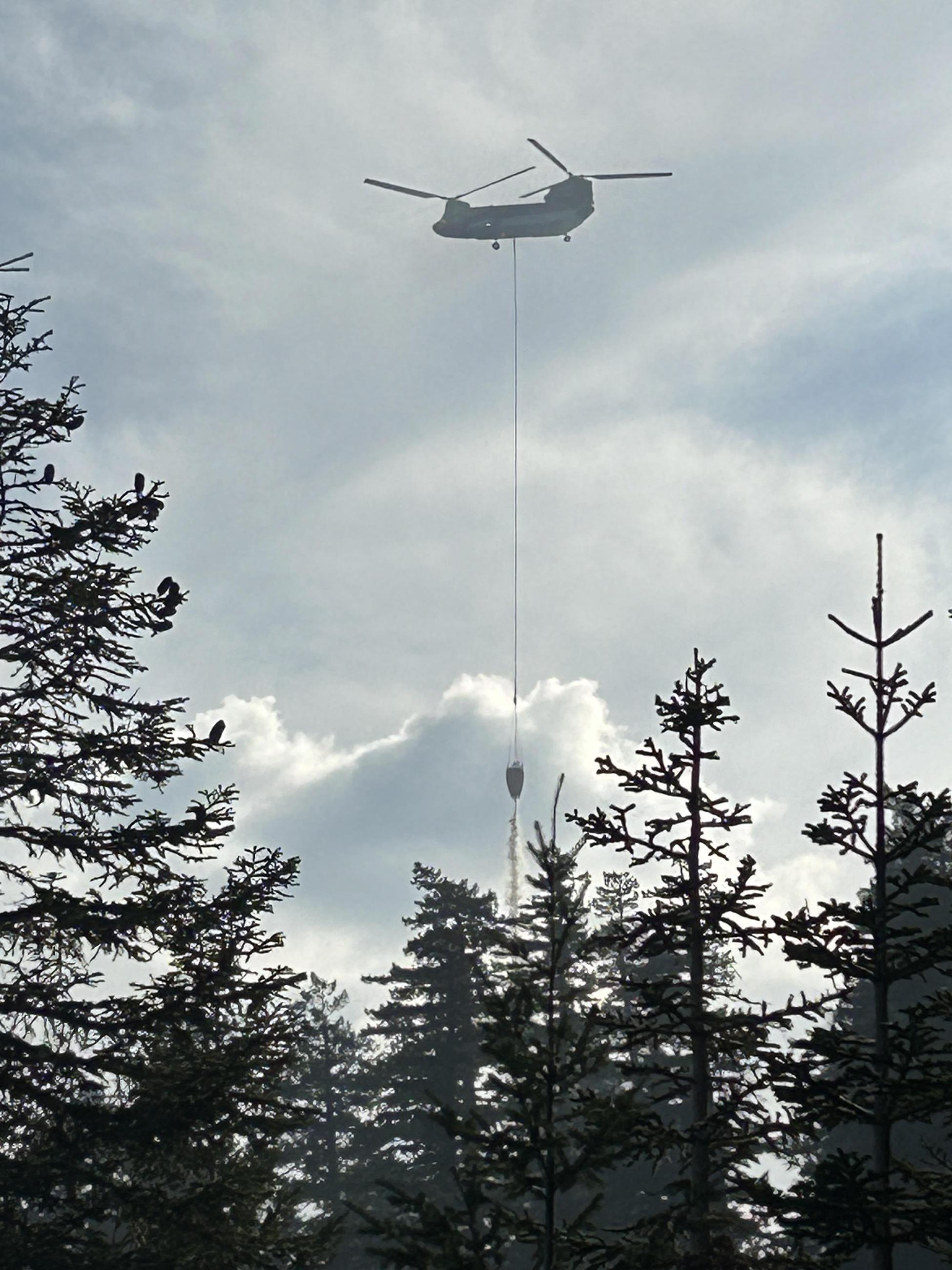 large helicopter flys with bucket