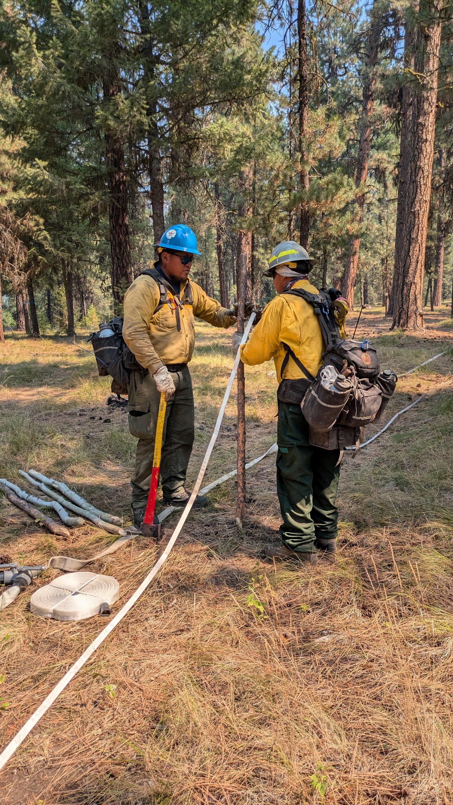 photo showing firefighters laying hose around fire