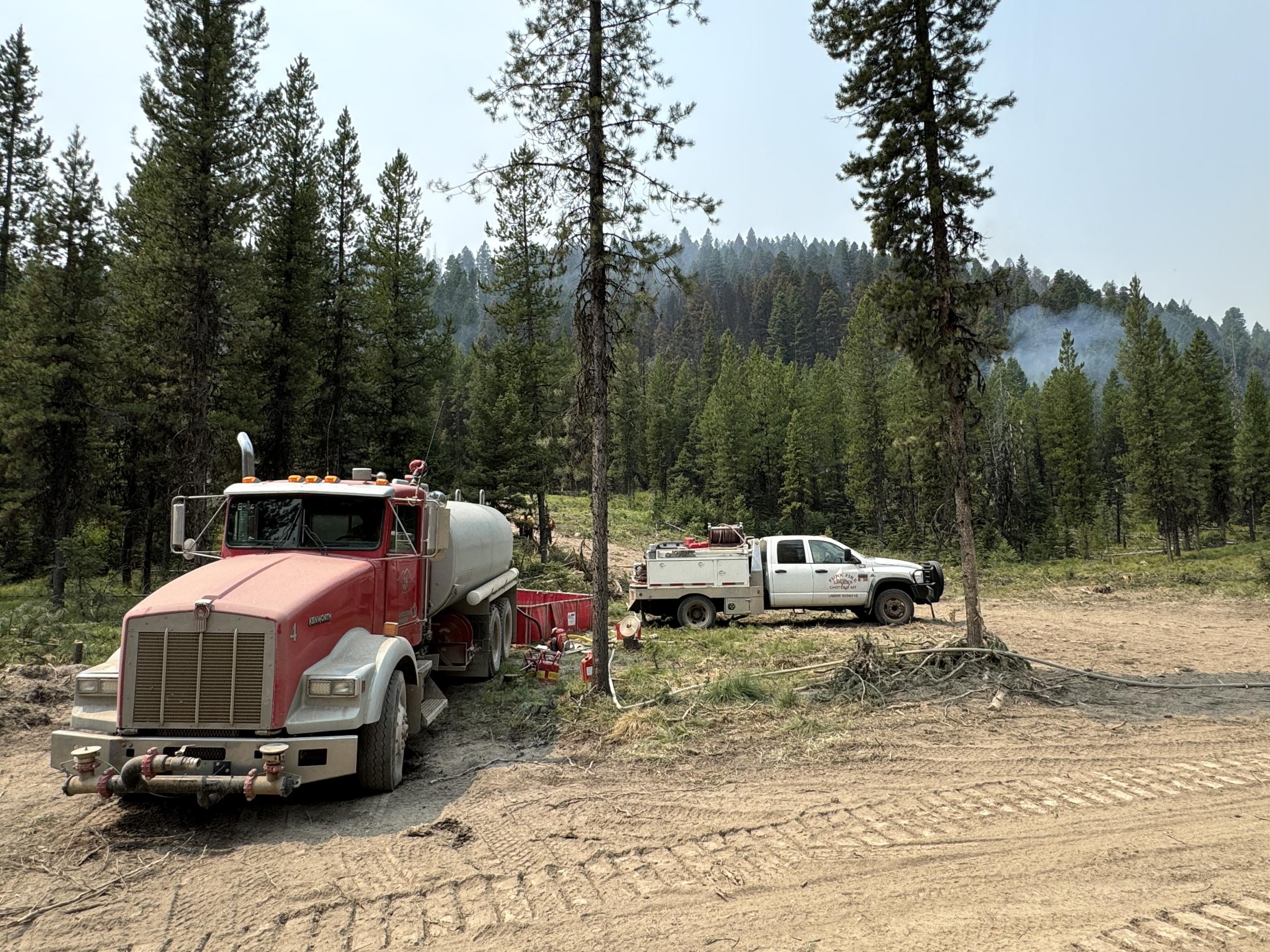 Water tender and engine at a portable water tank on the fireline.