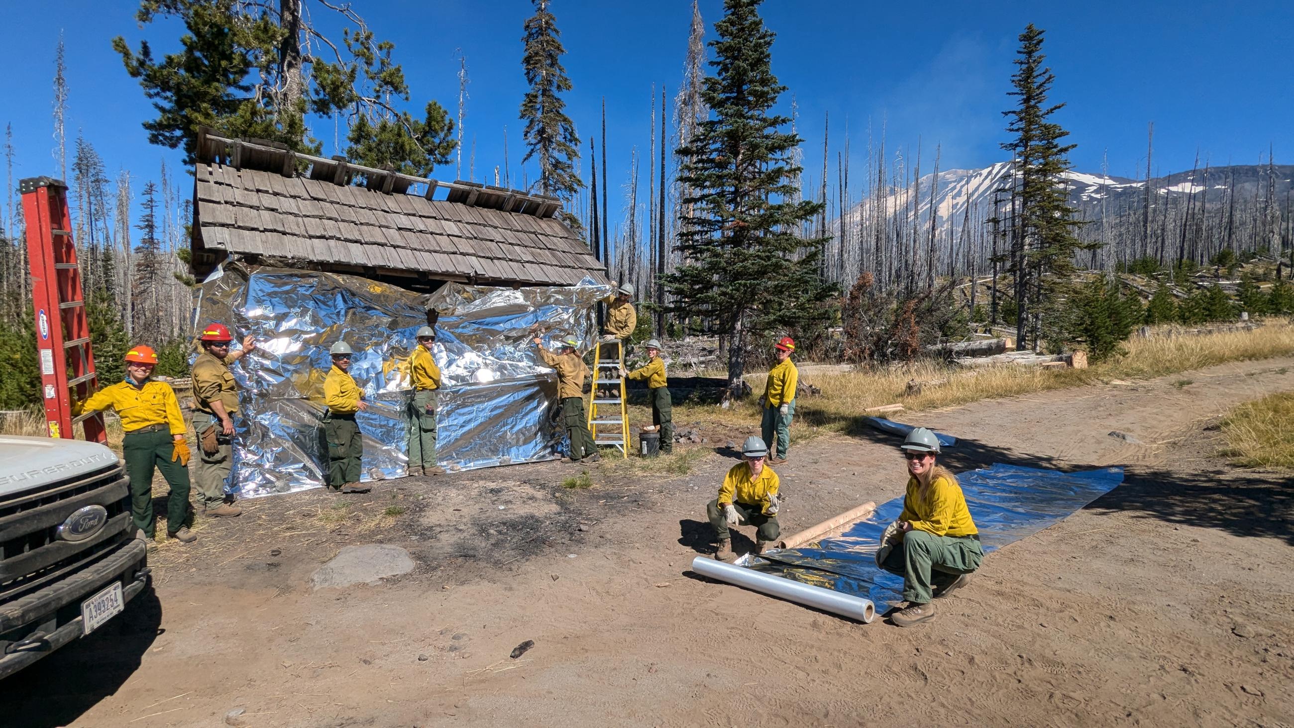 Fire personnel wrapping the Morrison Shelter with protective fabric 8-30-24