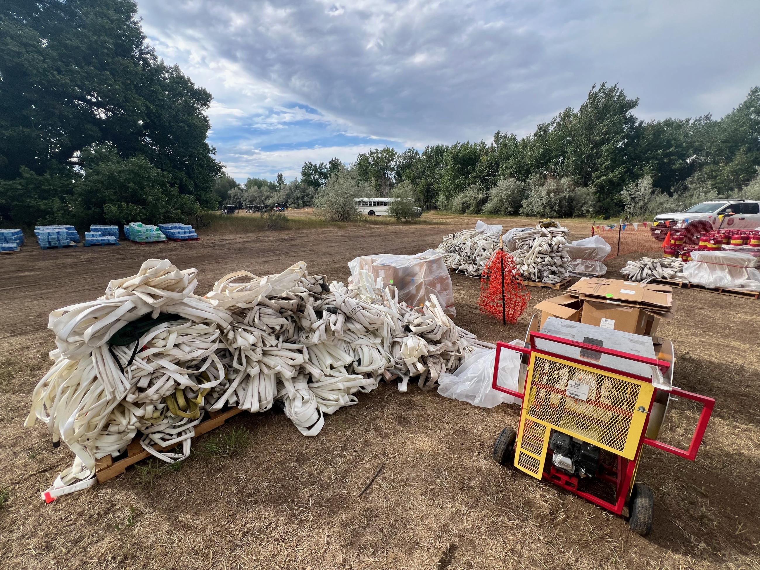 A jumbled pile of used fire hose is seen with a machine used to roll hose at right.