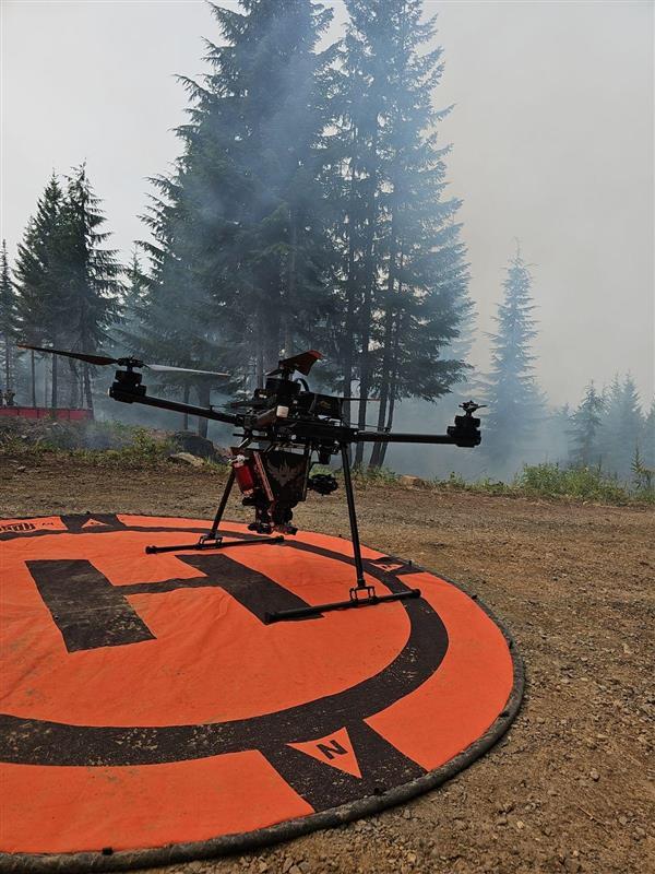 a drone capable of starting small fires used during fire operations hovers over its landing pad