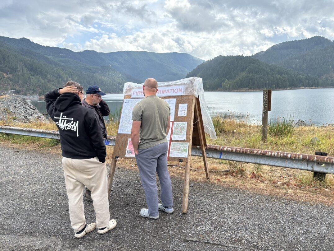 PIO Webb is standing by a fire information board sharing information with two members of the public