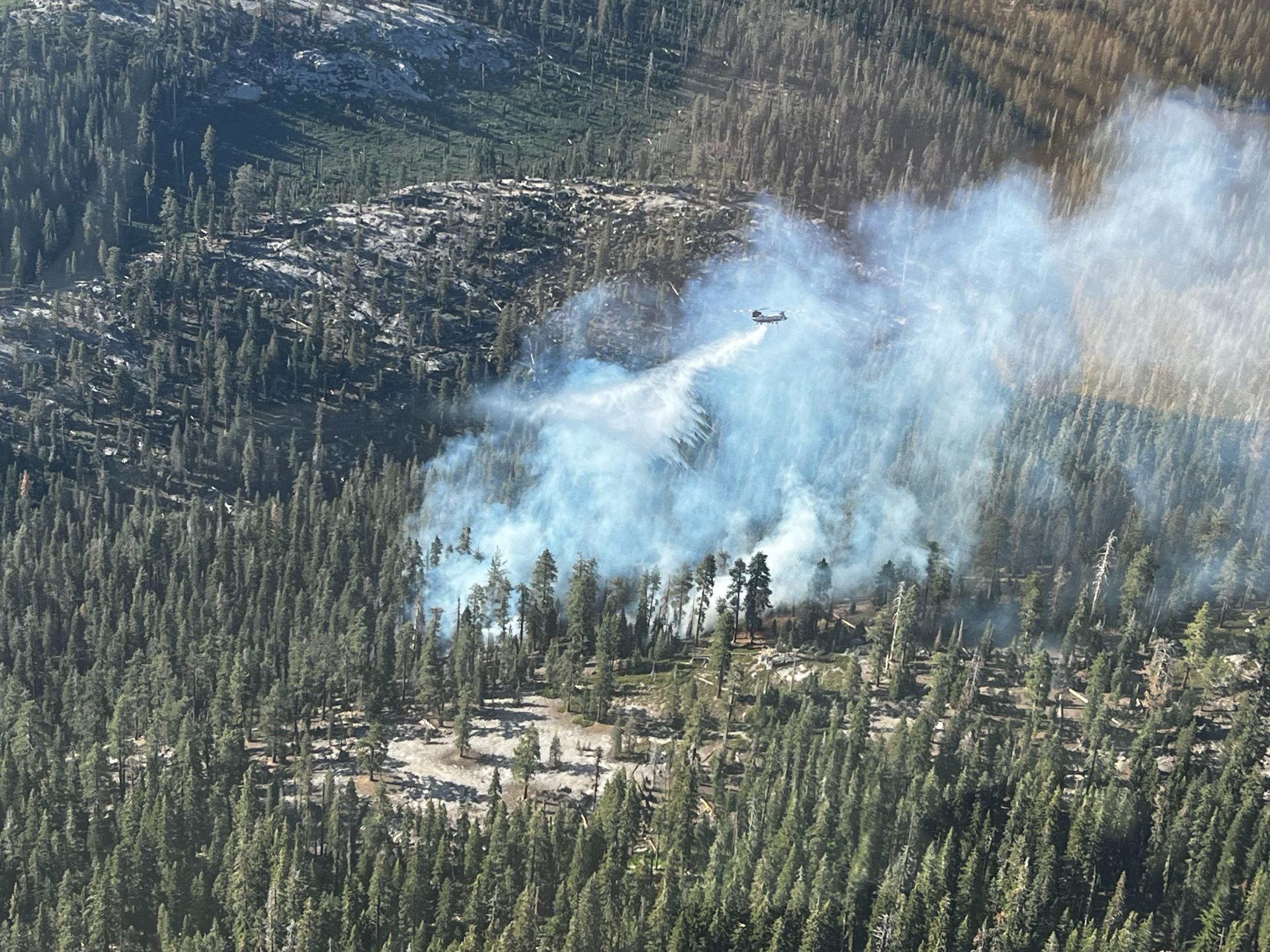 Helicopter dropping water on a wildfire, as seen from another helicopter