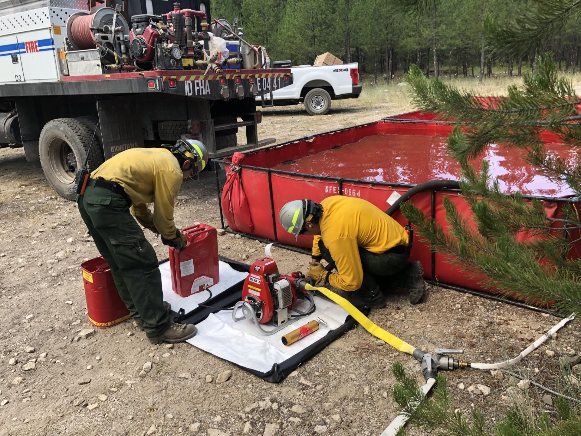 two wildland firefighters setting up a water pump