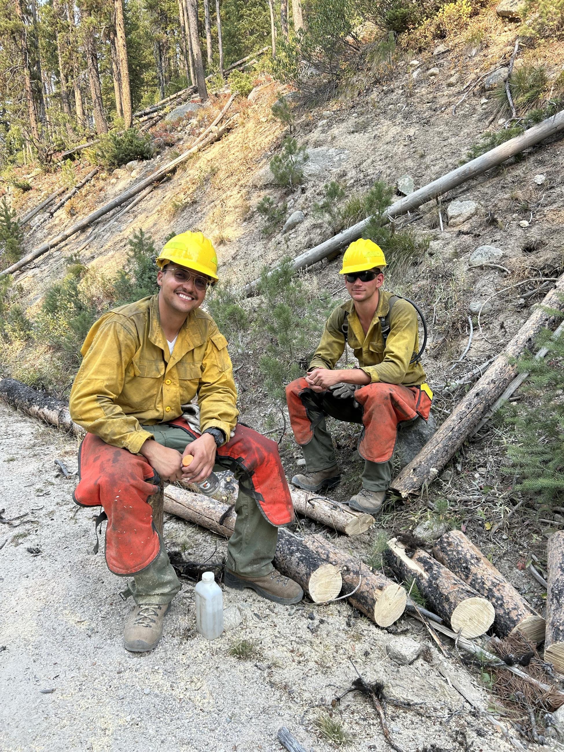 Two sawyers sitting on logs on the edge of the fireline