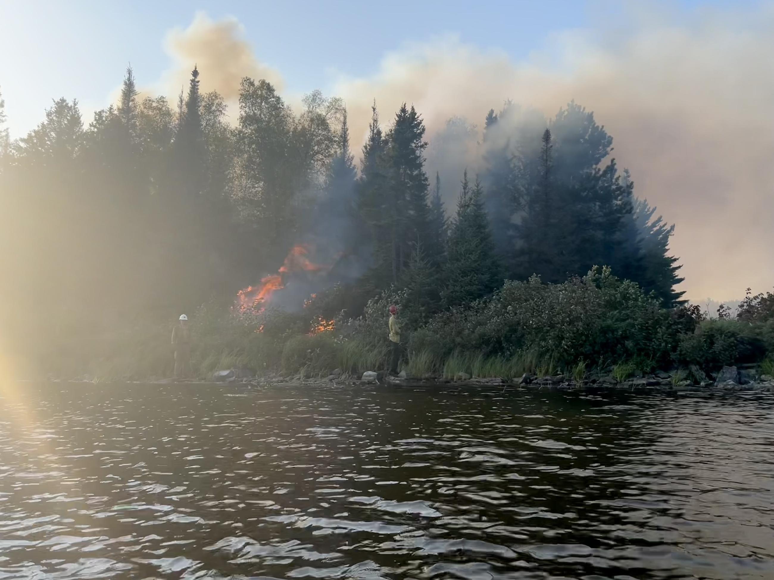 Firefighter stands on the shoreline of the Wood Lake Fire 