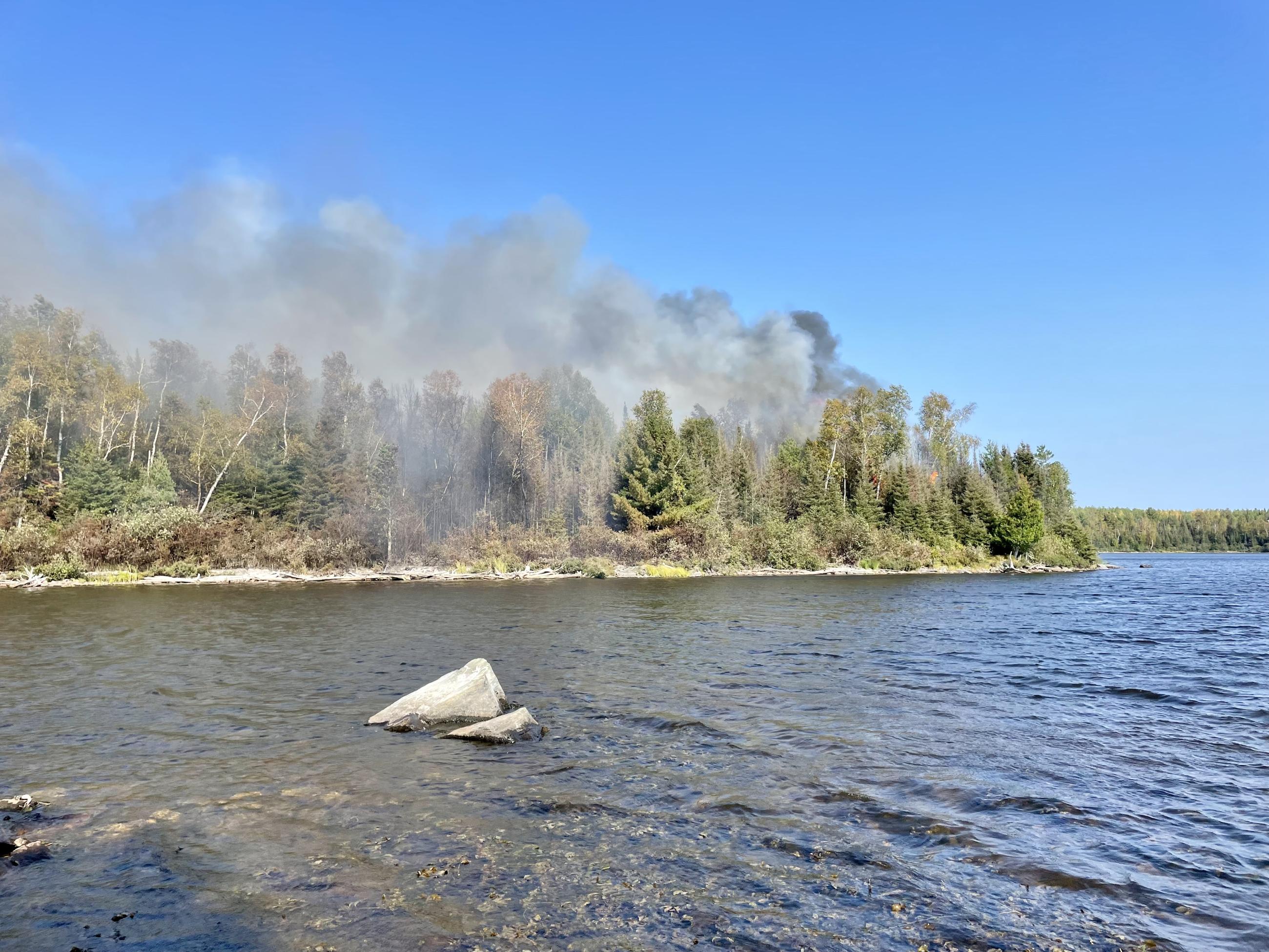 Smoke rising from a land point surrounded by lake and water 