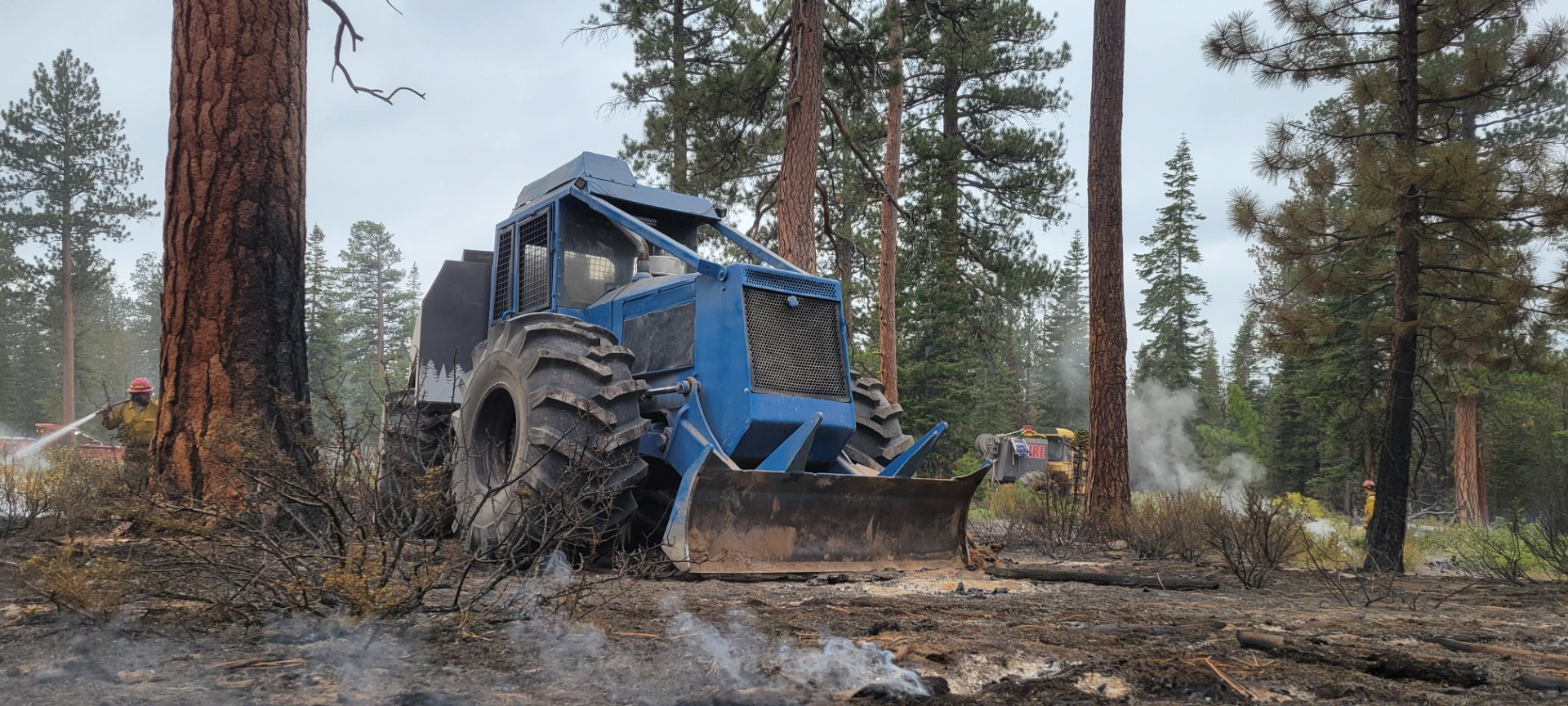 Firefighters working in combination with heavy equipment operators.