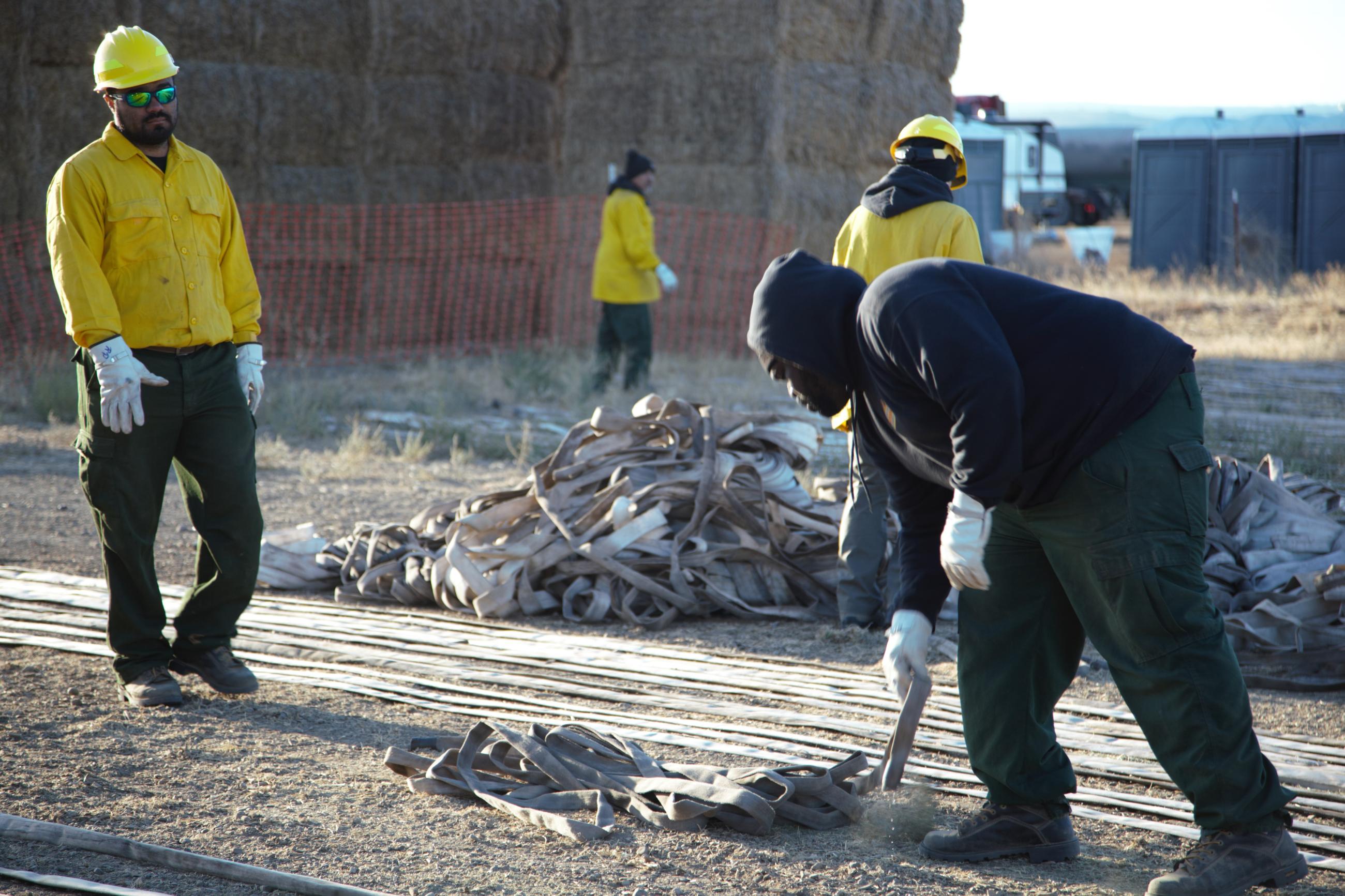 Firefighters roll and clean fire hose.