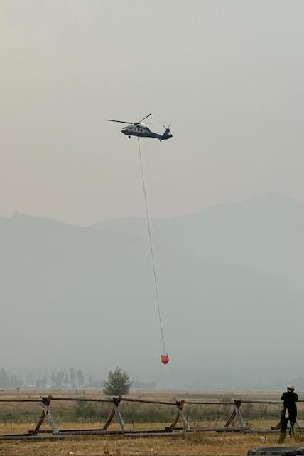 Heavy helicopter dipping water with a bucket on a long line