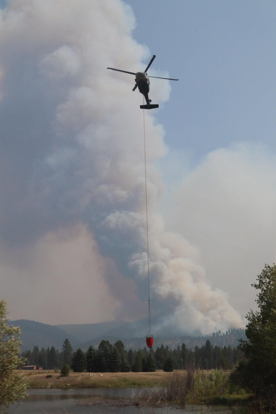 Helicopter Dips From Pond with Fire Column in Background