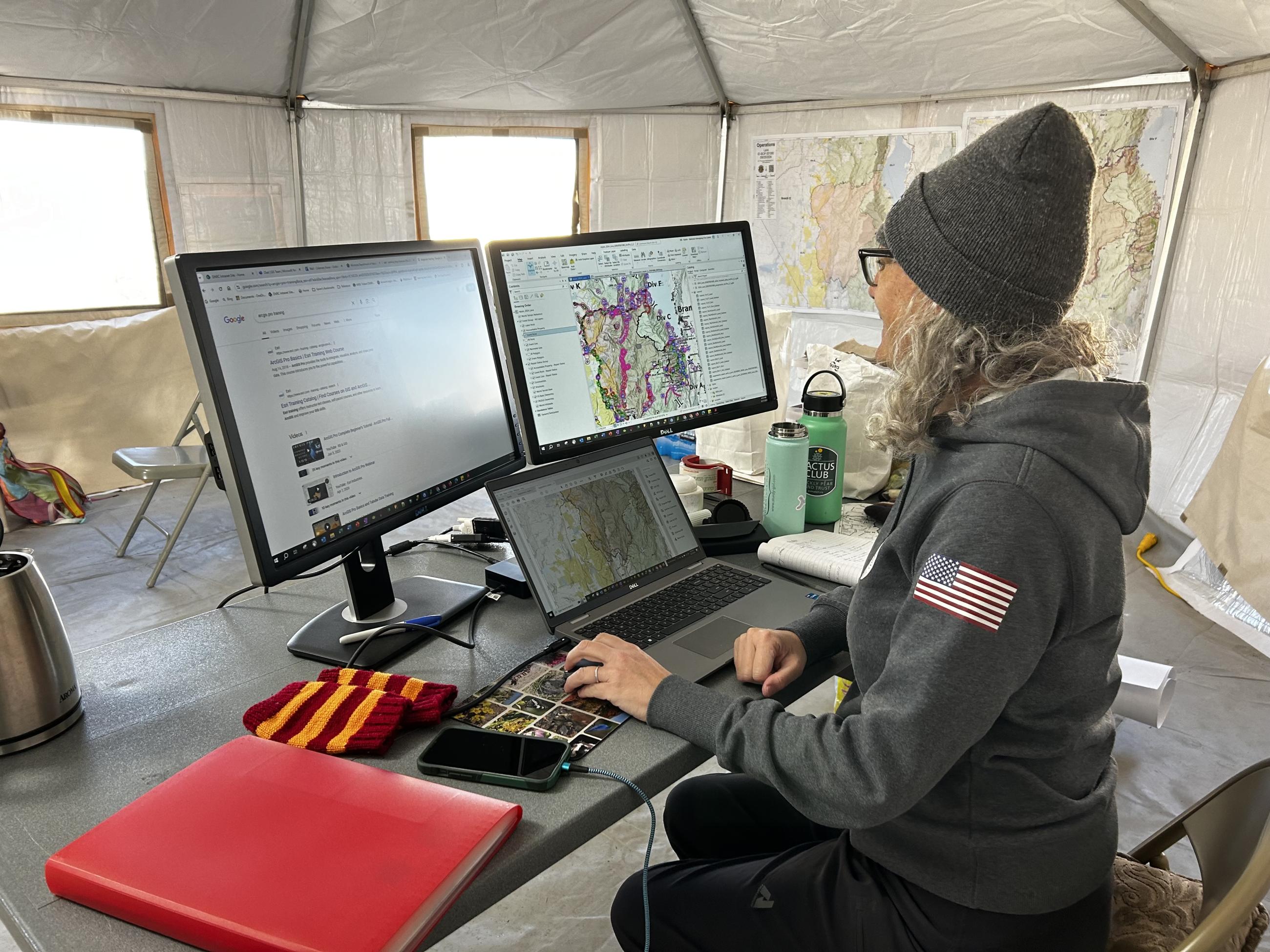 Woman standing at a computer showing maps and GIS software