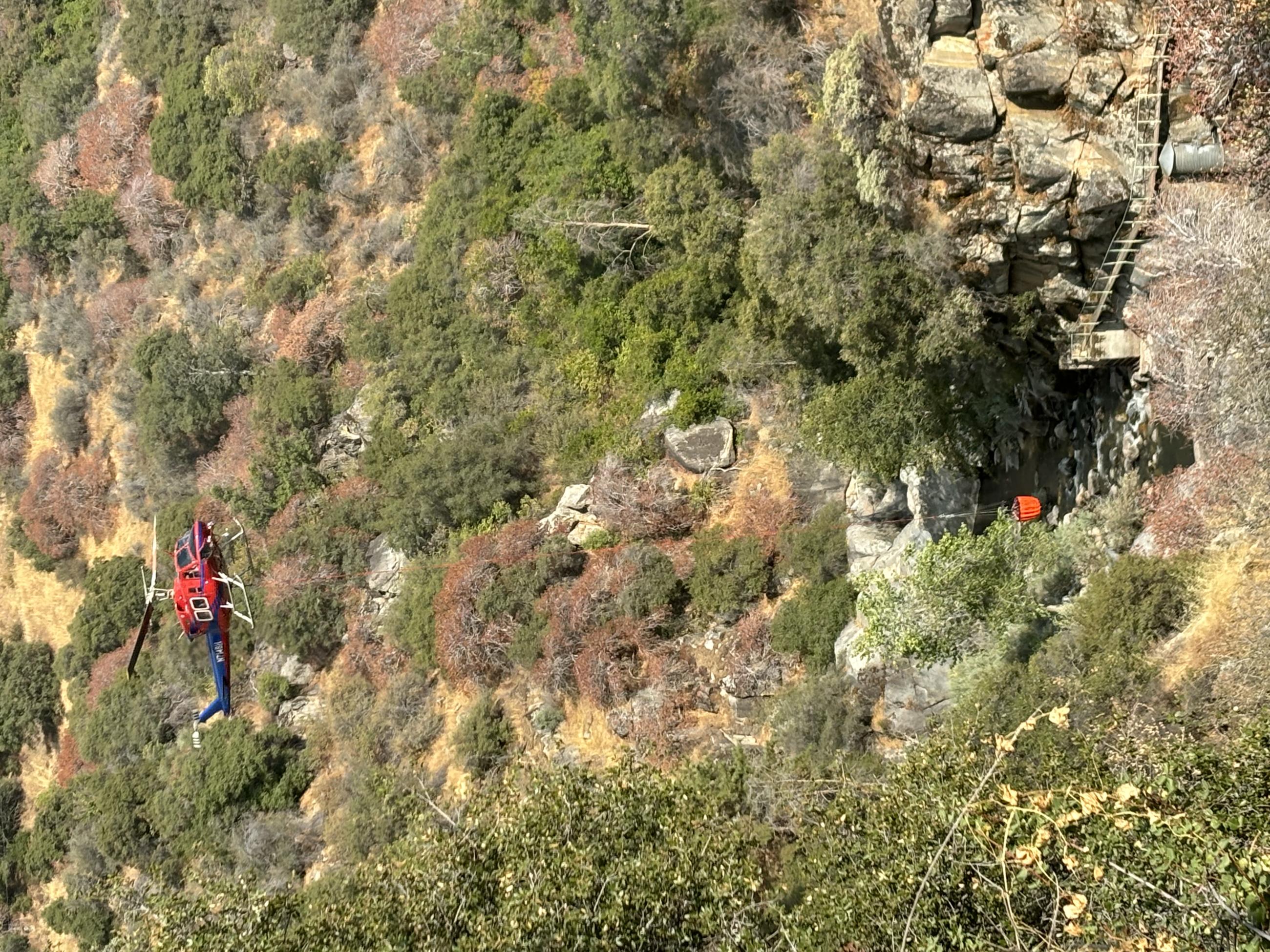 A helicopter and red bucket over a river 