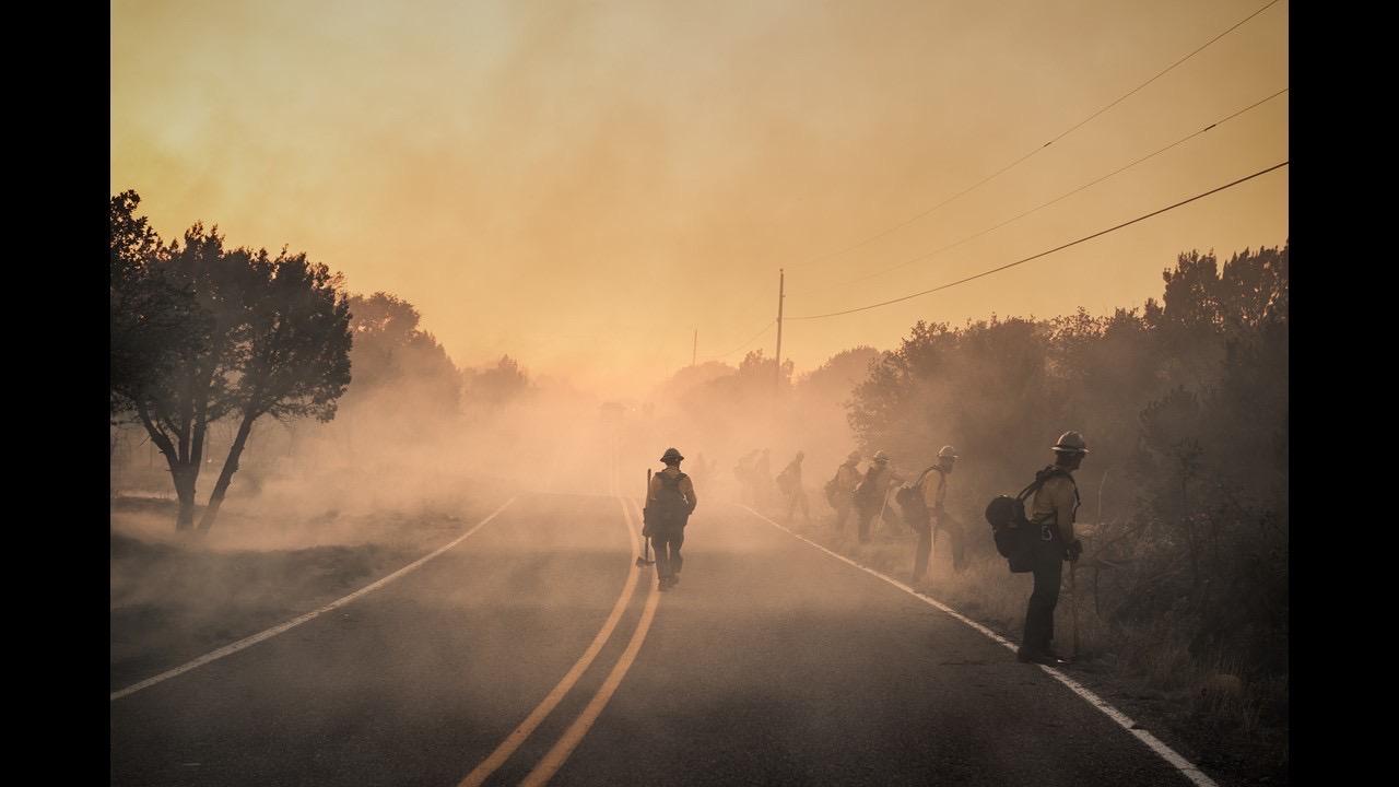 Firefighters conducting fire suppression repair work along a road.