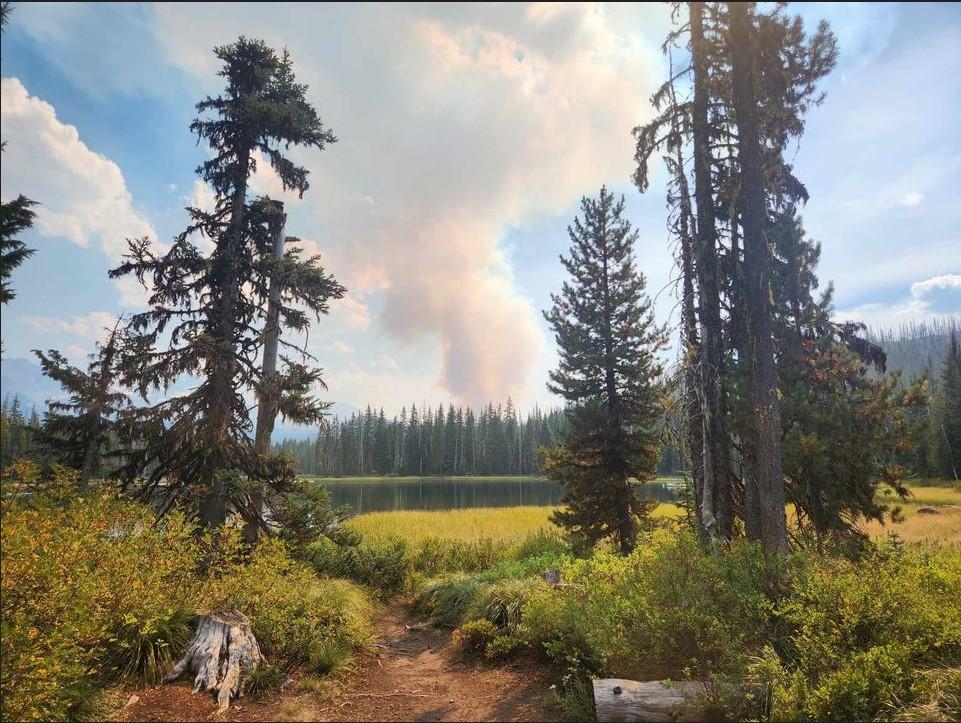 Smoke Rises over a lake and meadow.