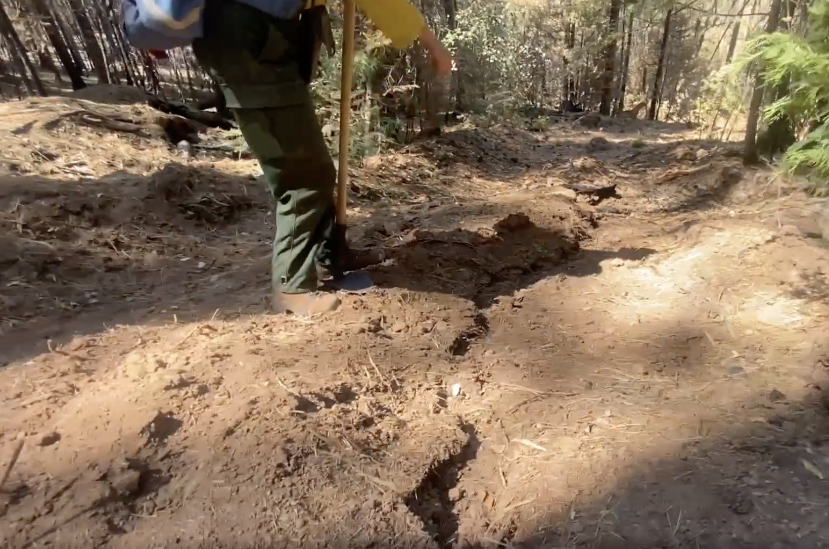 A photo showing Resource Advisor Cheyenne Laskey points to erosion which occurred after only one rain.