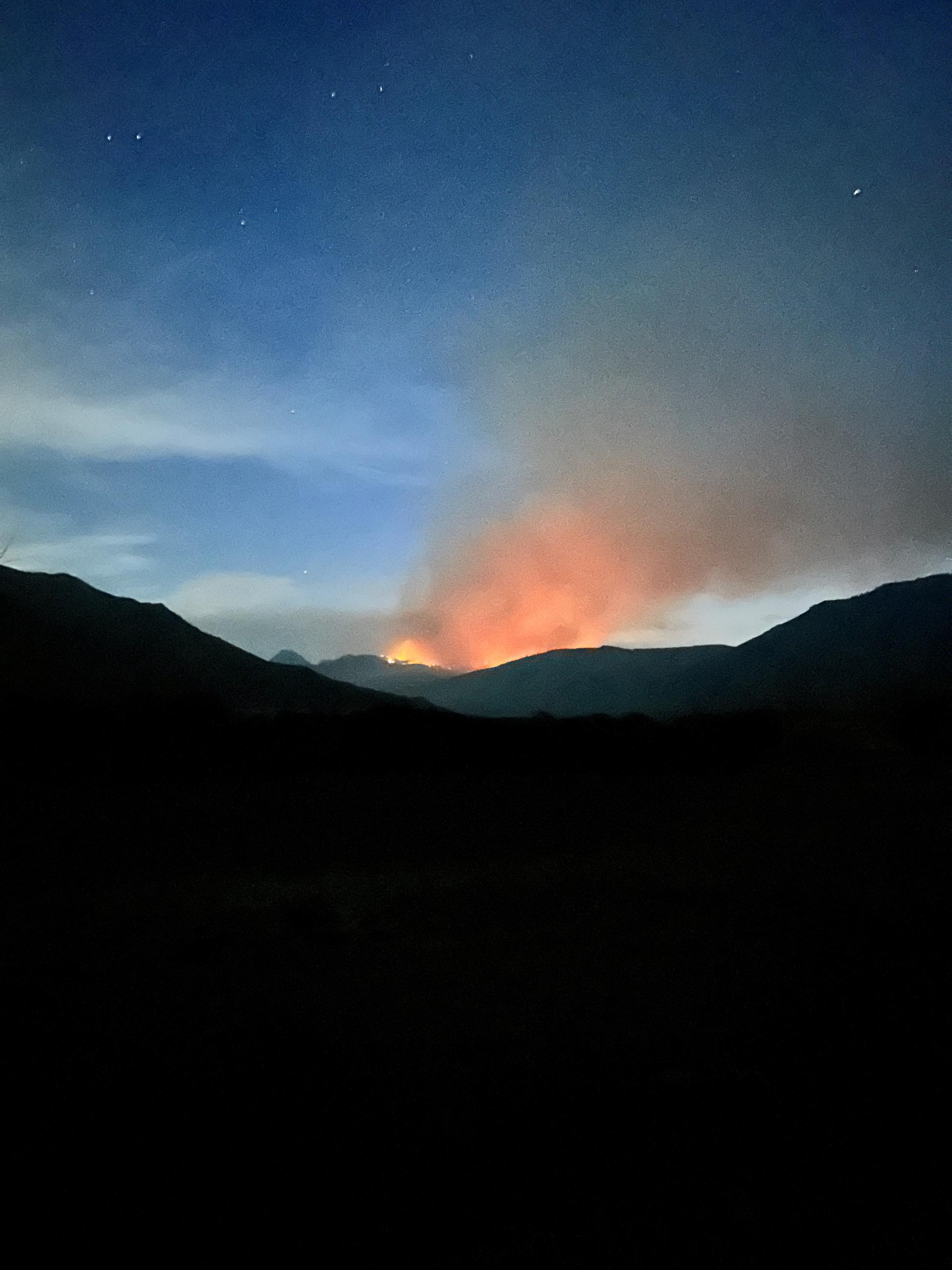 Fire glowing behind the hills at night