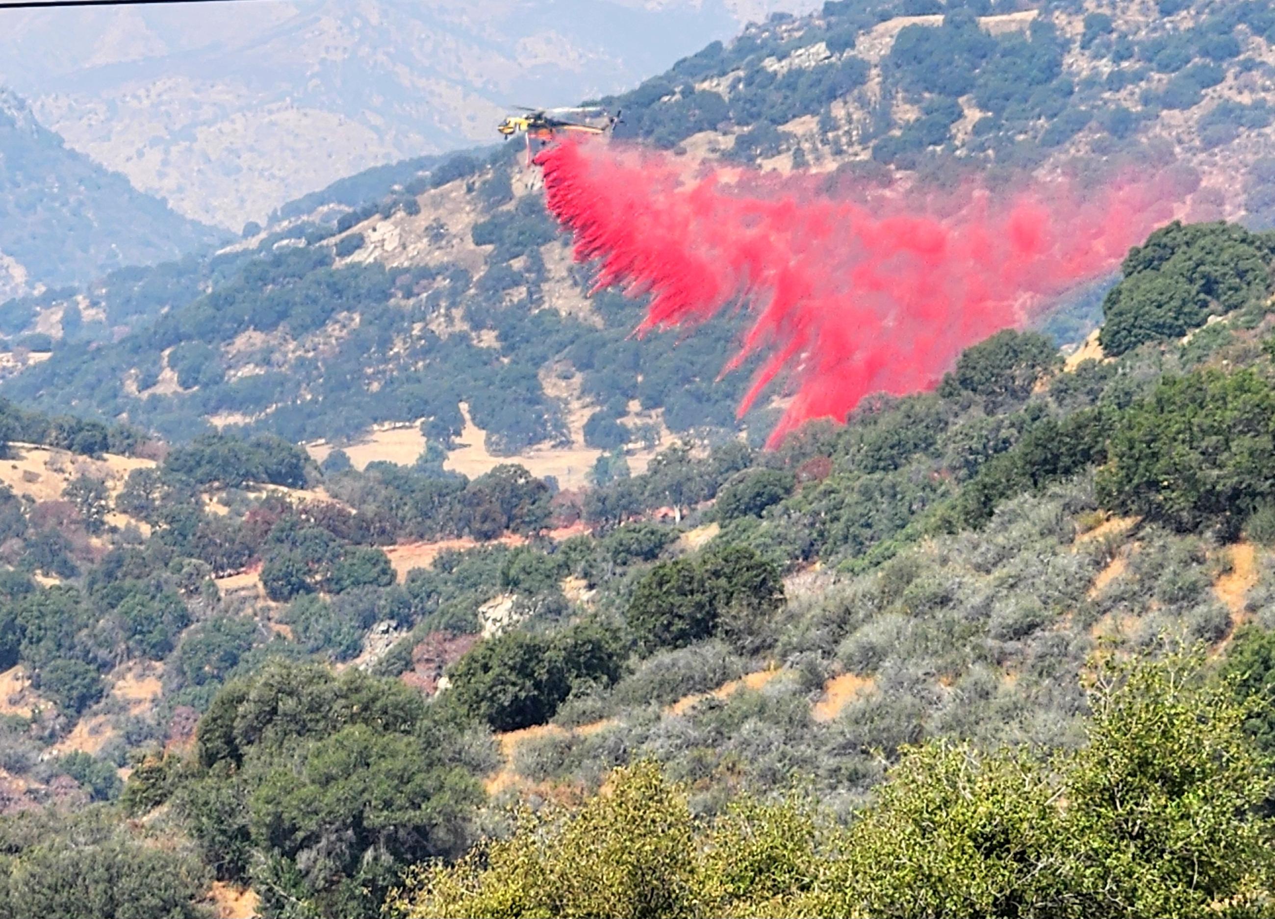 Sky crane helicopter dropping retardant on vegetation