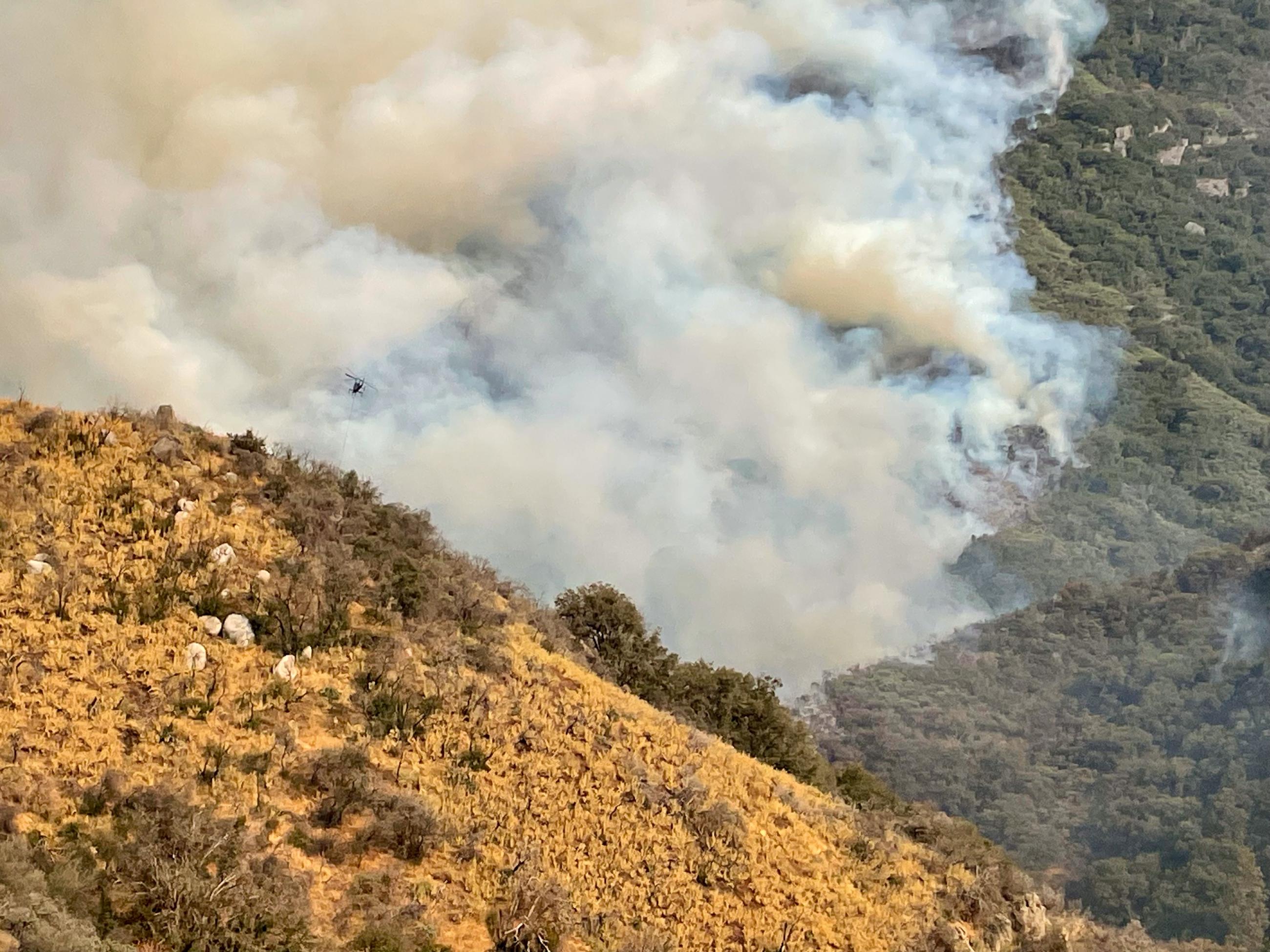 K-Max helicopter doing air operations. Heavy smoke pictured at lower grounds