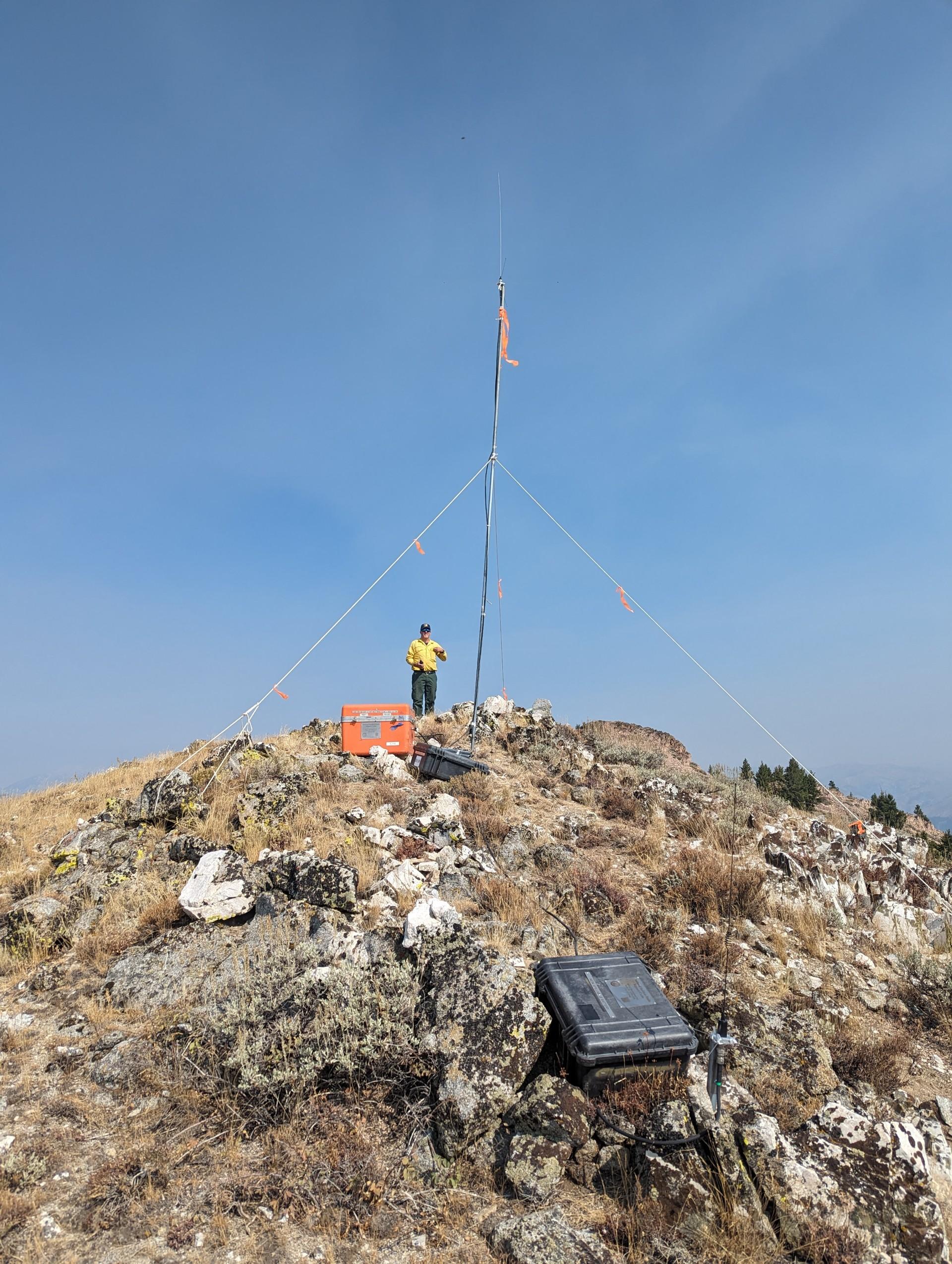 Firefighter standing next to communications repeater on a ridge top on the Chimney Fire