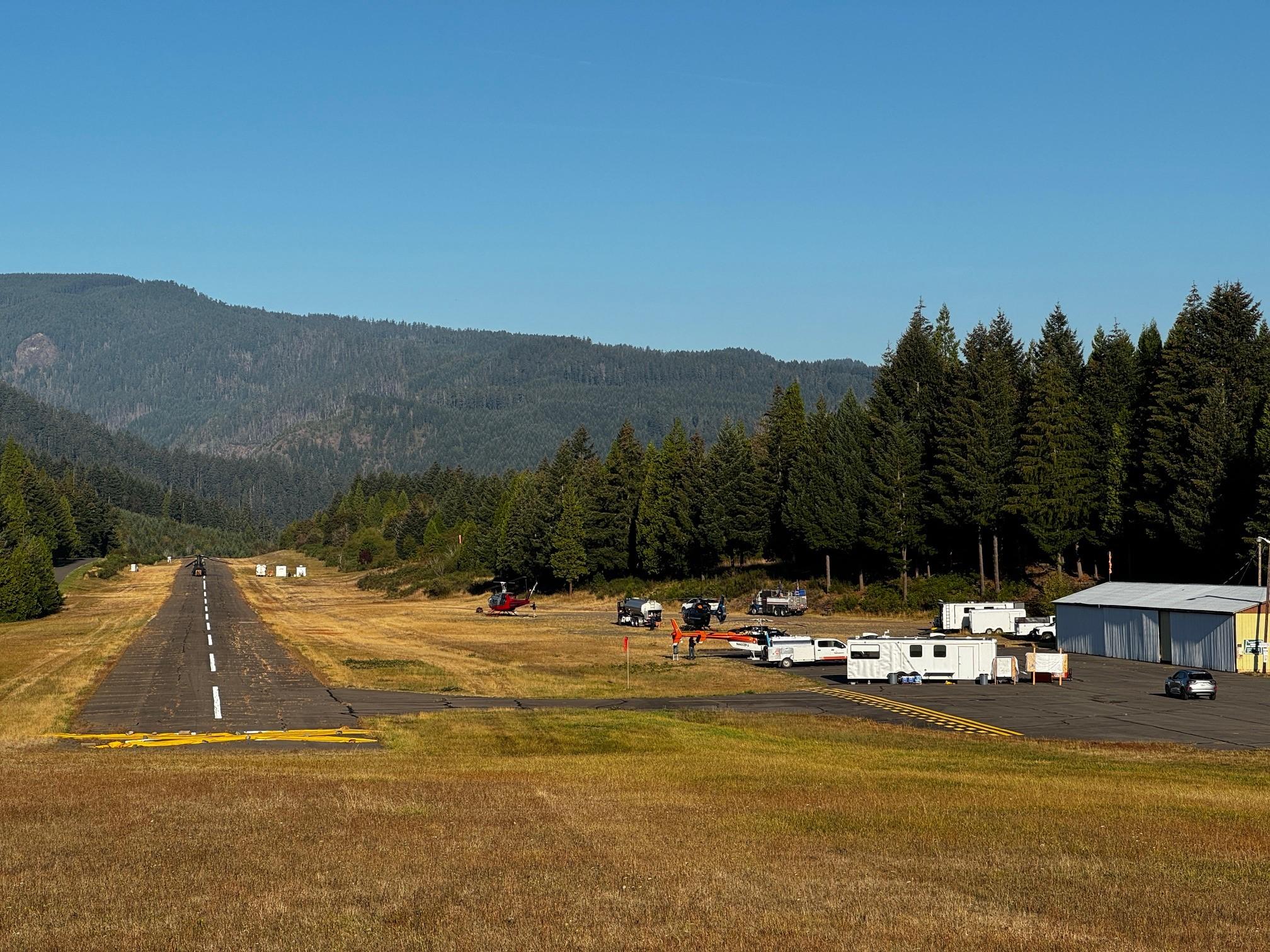 View of the airstrip being used as a helicopter base in Oakridge Oregon with mountains and forest in the background