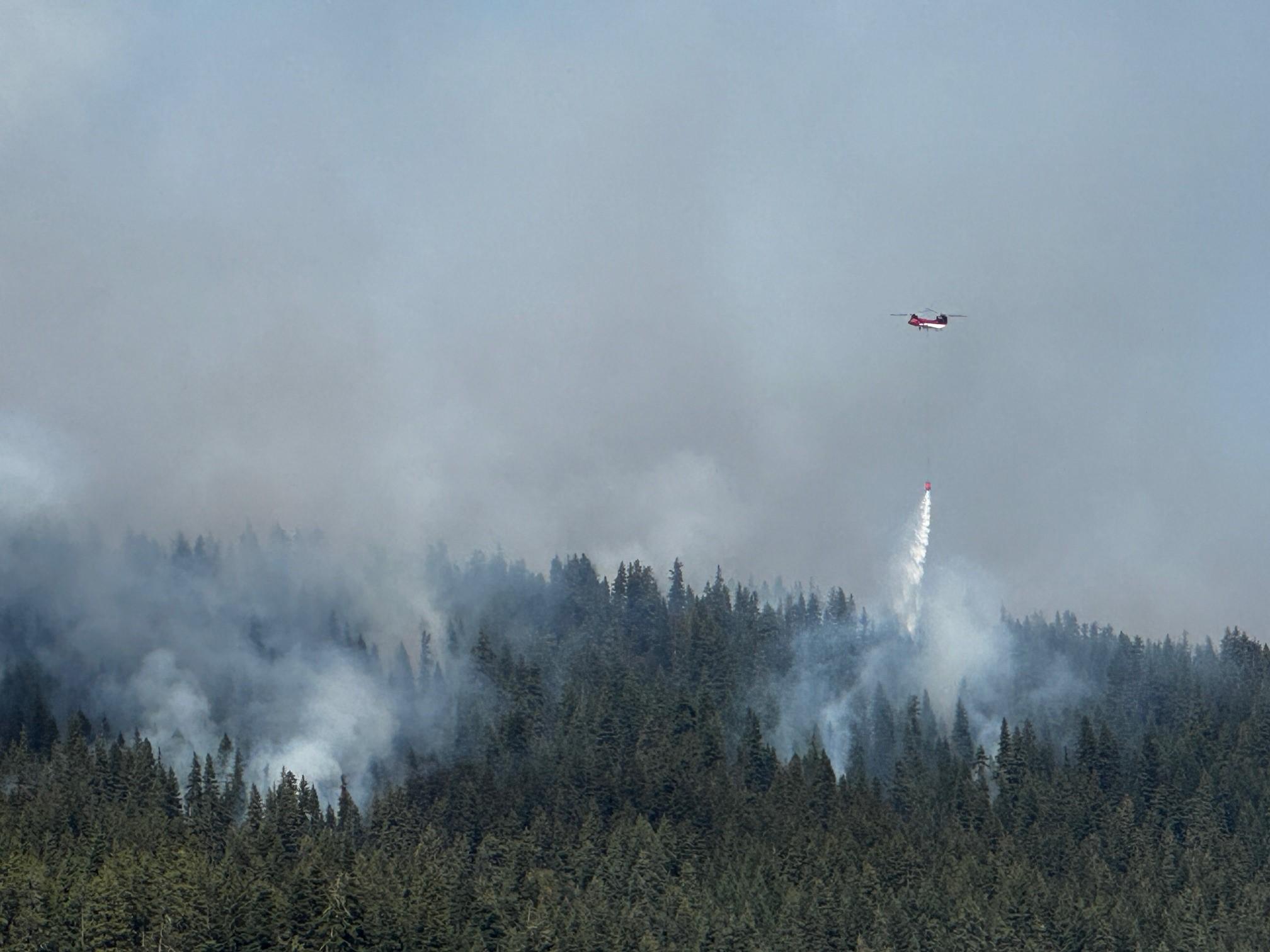 Helicopter dropping water on a wildfire in a forest