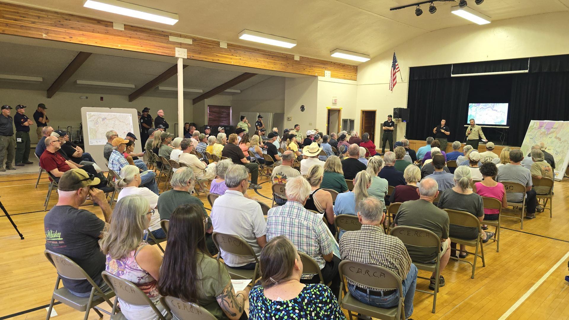 people sitting in chairs in a large room listening to a presentation