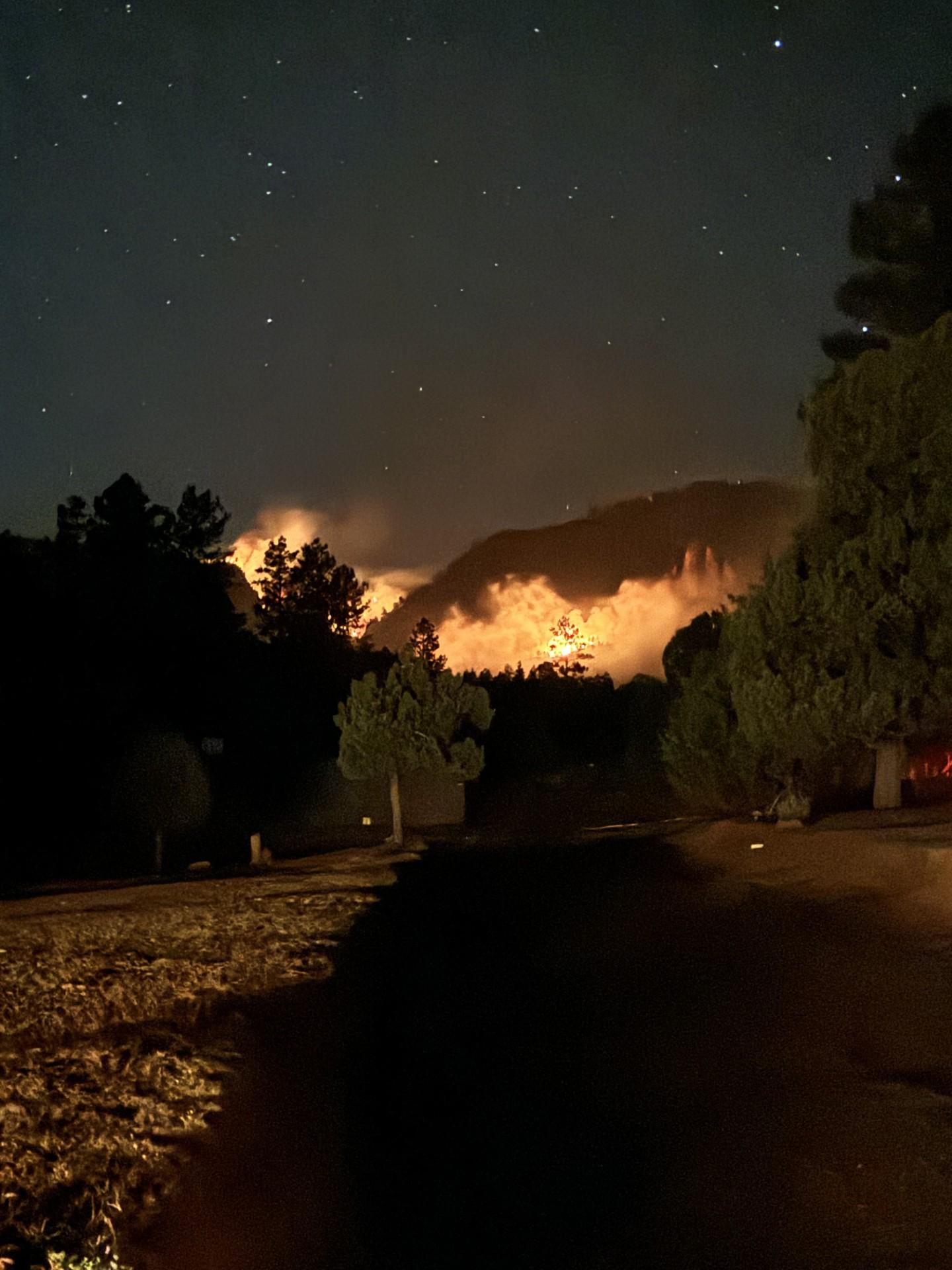 Dark night image shows fire burning on the mountainside