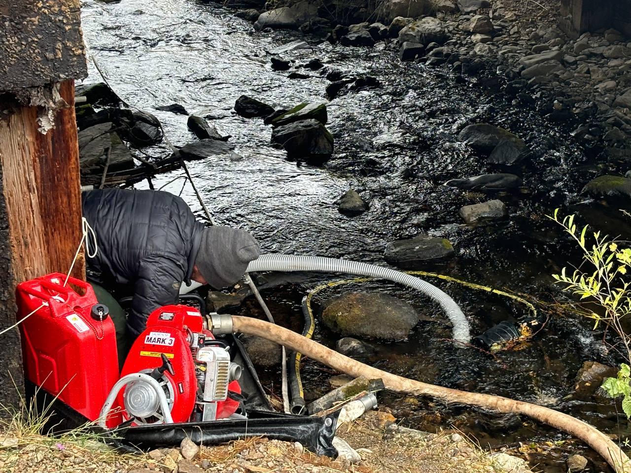 Firefighter using a pump to draft water from a creek.