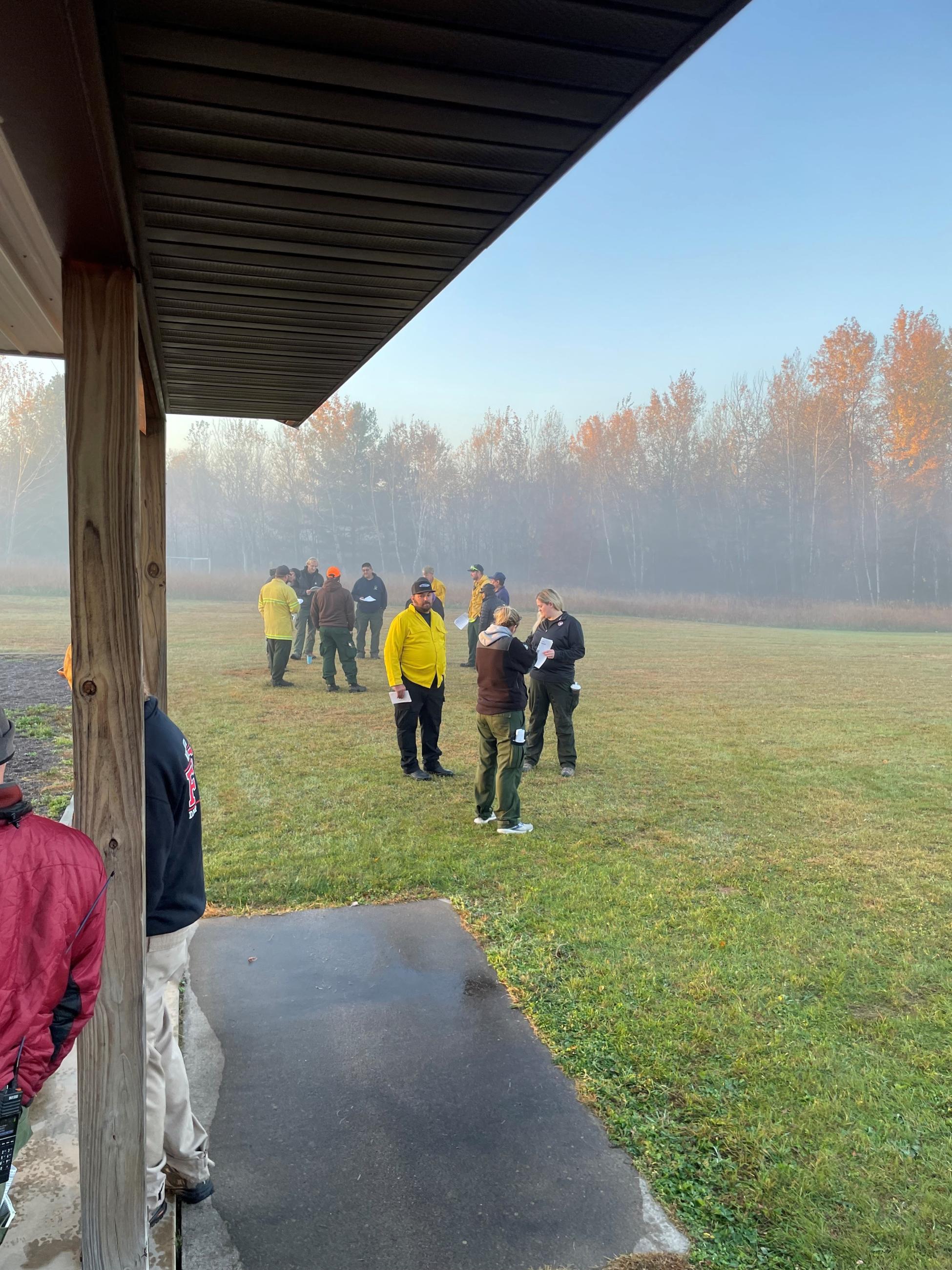 People in a field by a pavilion in the morning 