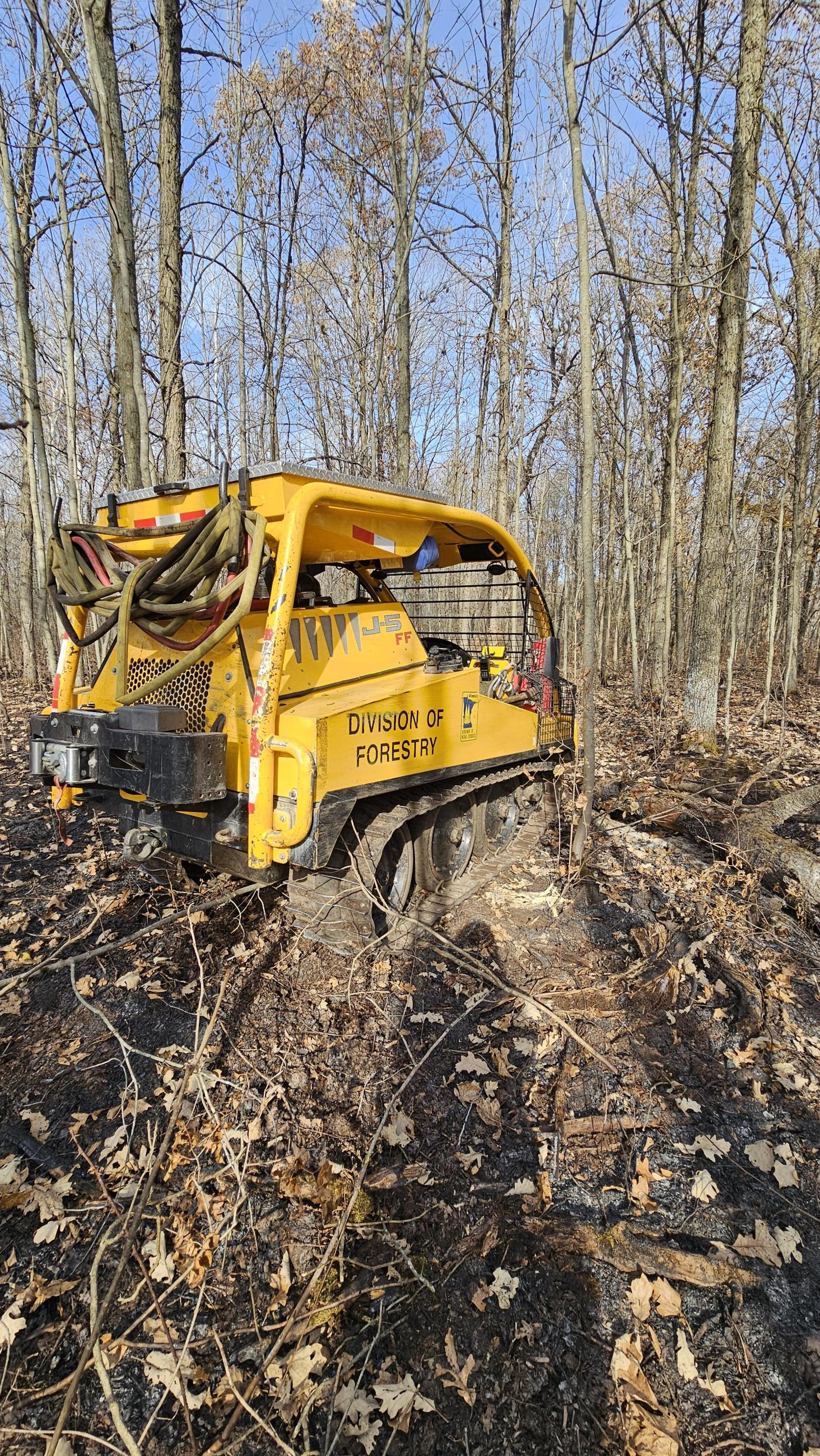 A yellow tracked machinery in the forest. 