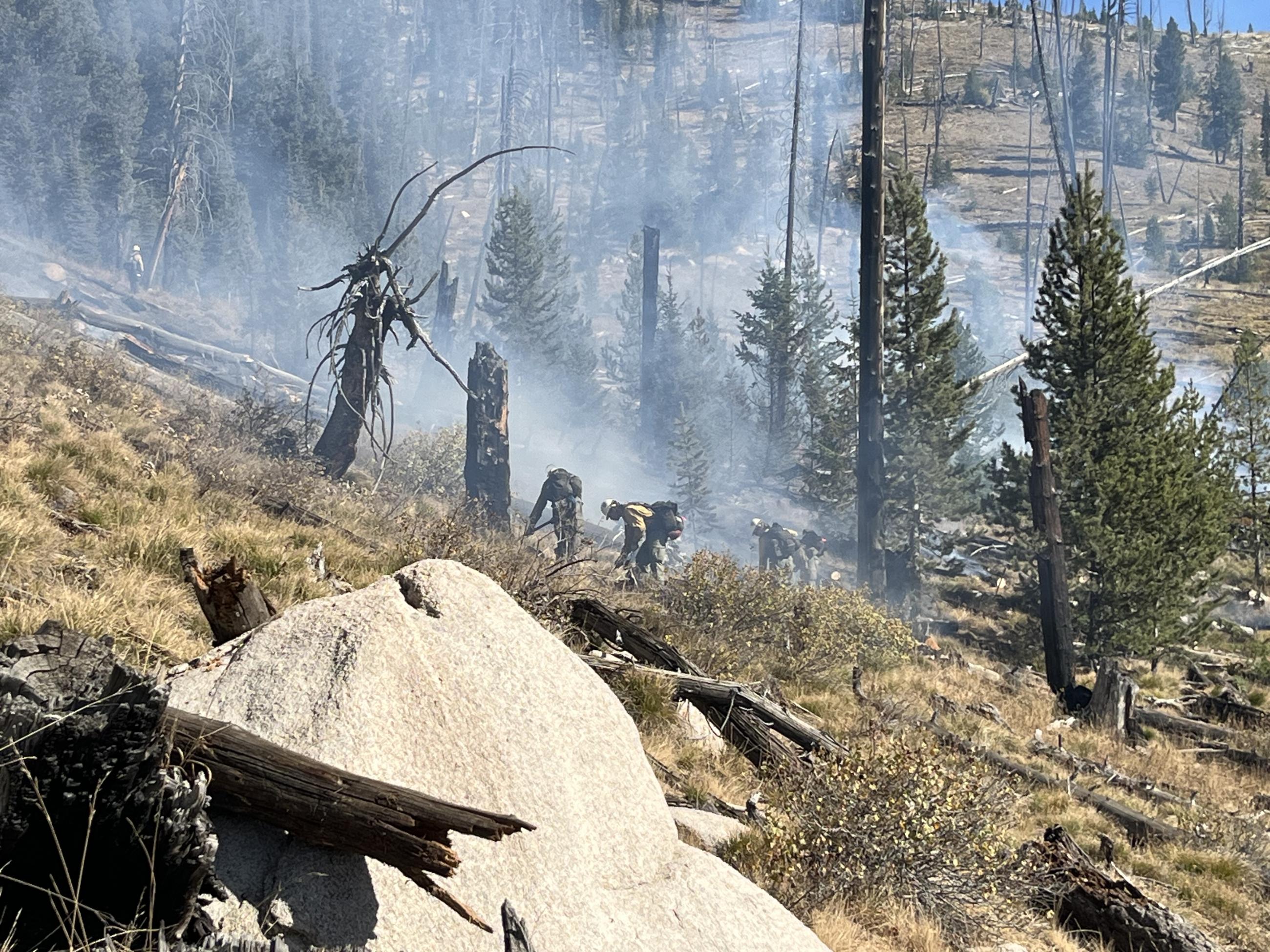 hillside with firefighters working in smoke